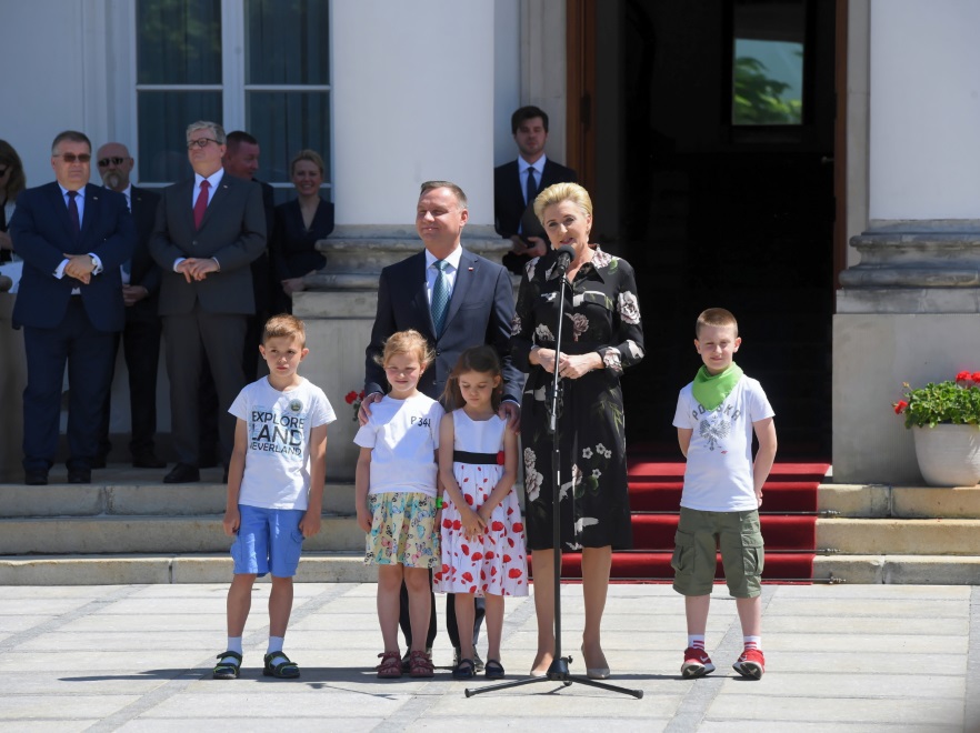 ... z nieba lał się prawdziwie letni żar. Przy tej pogodzie ciemna mocno zabudowana sukienka pierwszej damy wydawała się wyjątkowo przytłaczająca i ciężka...