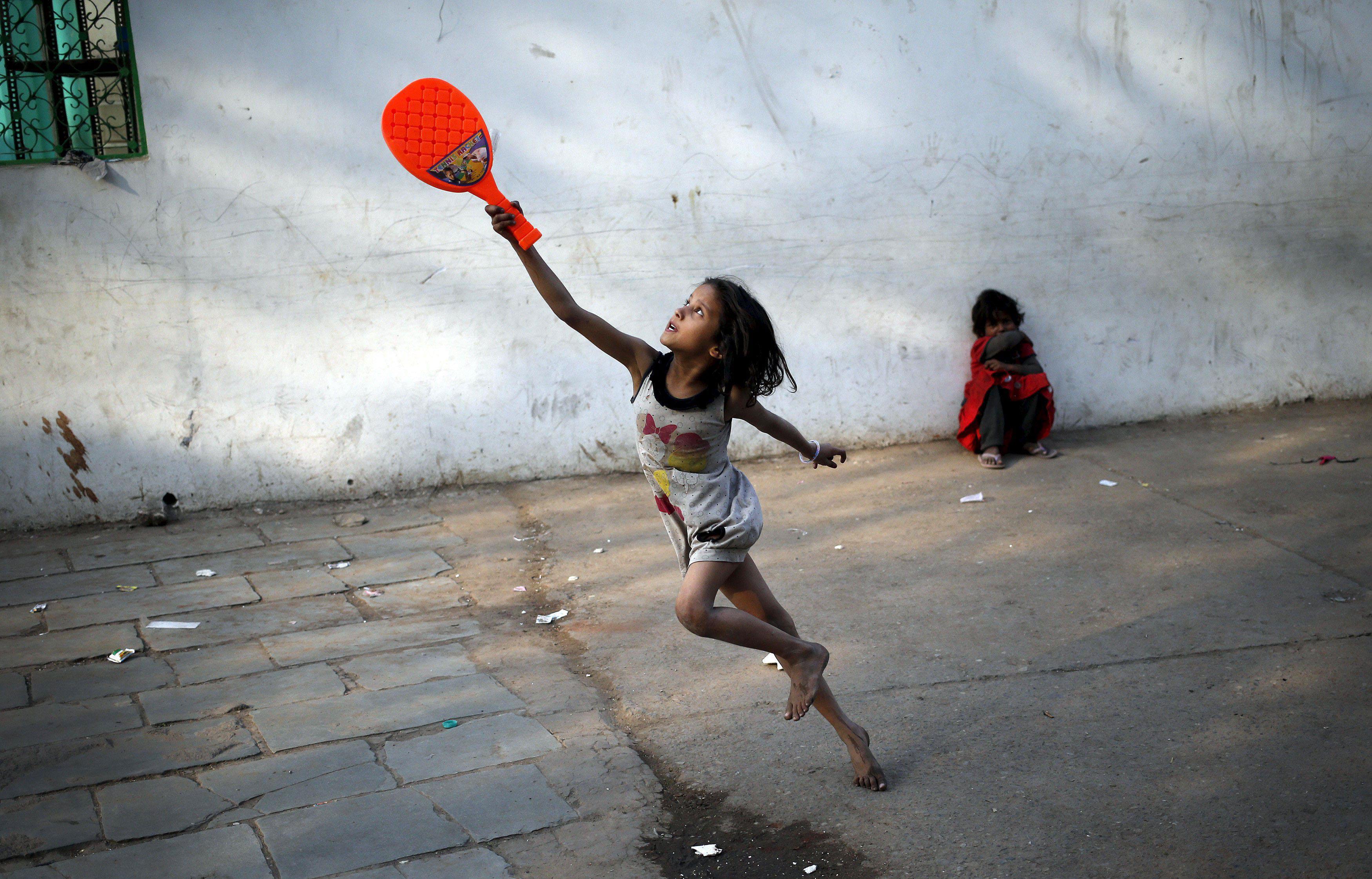 A child plays with a plastic badminton racket in the old quarters of Delhi