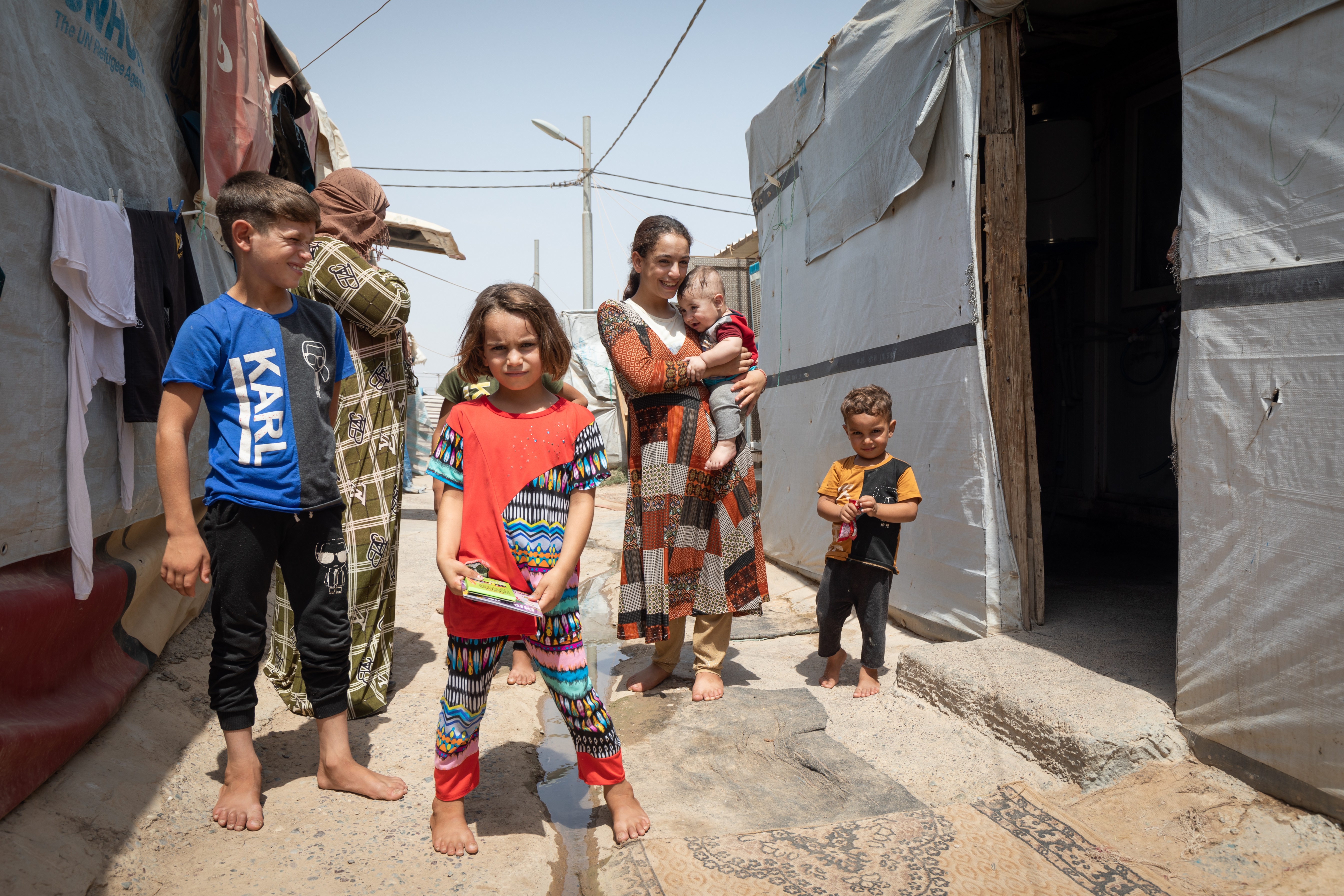 Baharka. Wansa Suliman ma pięcioro mniejszych dzieci i dwóch dorosłych synów. Uciekła przez ISIS z okolic Mosulu. Jako jedna z nielicznych w obozie nie ma w kontenerowym domu klimatyzacji. Przesiaduje więc całymi dniami w domu starszego syna, który założył już własną rodzinę. 