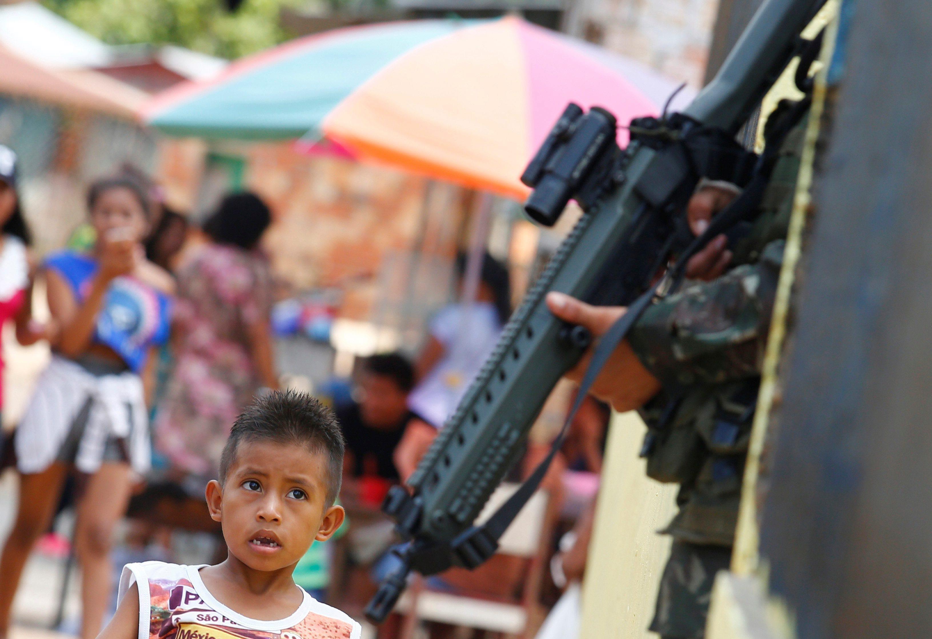 An indigenous boy observes a Brazilian army soldier, as he takes part in a joint military training f