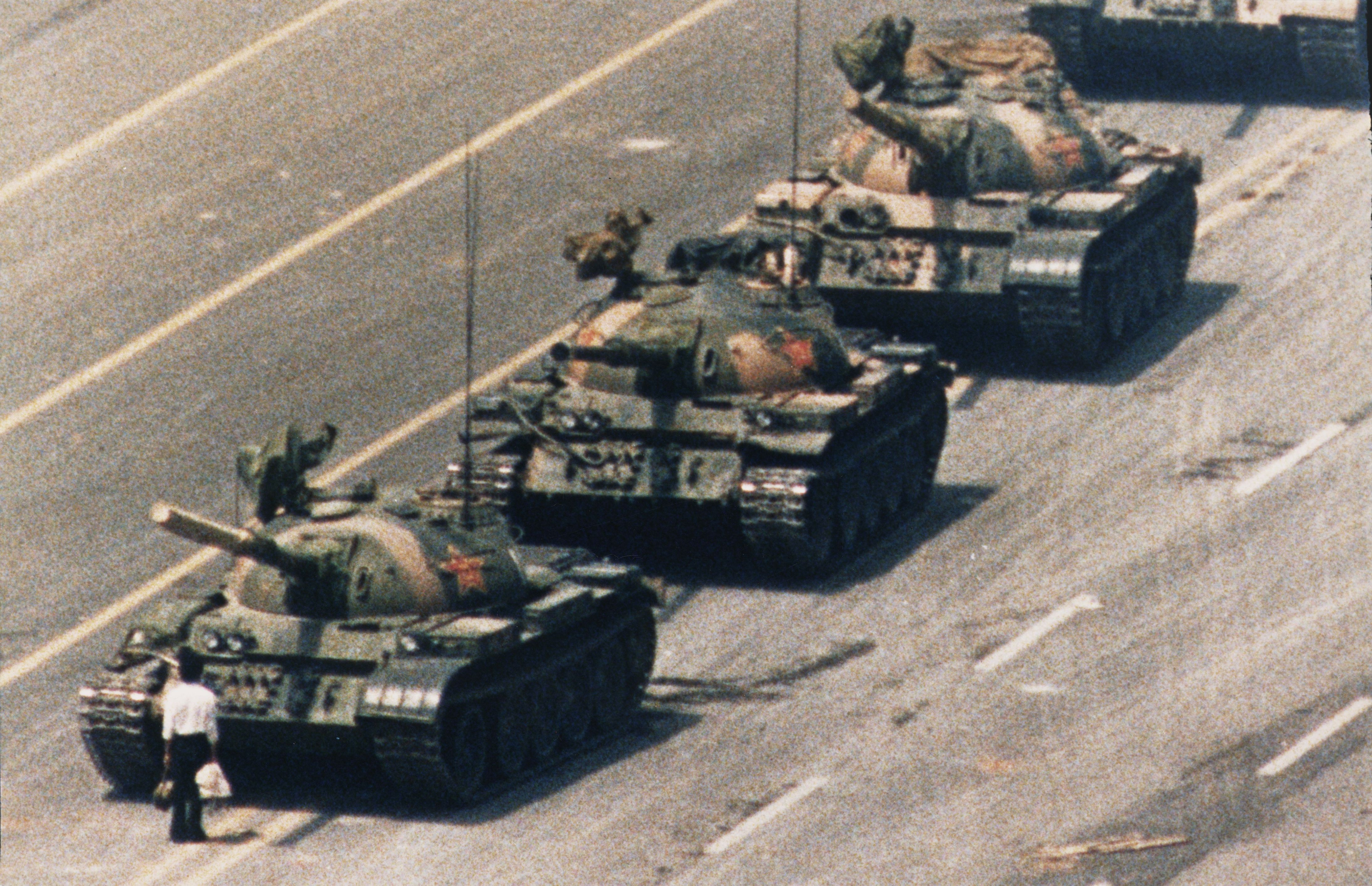 Jedna z najbardziej znanych fotografii świata, która stała się symbolem nie tylko protestów na placu Niebiańskiego Spokoju w Pekinie, ale i oporu wobec władzy totalitarnej. Między 15 kwietnia a 4 czerwca 1989 roku w Pekinie studenci głośno domagali się demokratycznych reform. Najpierw była manifestacja ku czci zmarłego sekretarza generalnego Komunistycznej Partii Chin Hu Yaobanga, w którym widziano szansę na reformy. Potem, w miarę radykalizowania się formy protestu - głodówka, a potem okupacja placu - narastały także żądania. Gdy władze uporały się z wyborem następcy Hu, przeważyła opcja rozwiązania siłowego. W nocy z 3 na 4 czerwca na Plac Tiananmen wysłano czołgi i żołnierzy uzbrojonych w broń maszynową. Zginęło - wedle różnych danych - od 241 do nawet dwóch tysięcy osób. Oficjalna propaganda podała, że użyto broni, ponieważ pokojowo nastawieni wojskowi zaatakowani zostali przez agresywnych studentów. W 2009 roku Human Right Watch podał, że w więzieniach wciąż pozostaje około 30 z setek uwięzionych po protestach osób. Zdjęcie zrobione przez Charliego Cole'a stało się symbolem - bezbronny mężczyzna zagroził drogę czołgom. / autor: Charlie Cole /