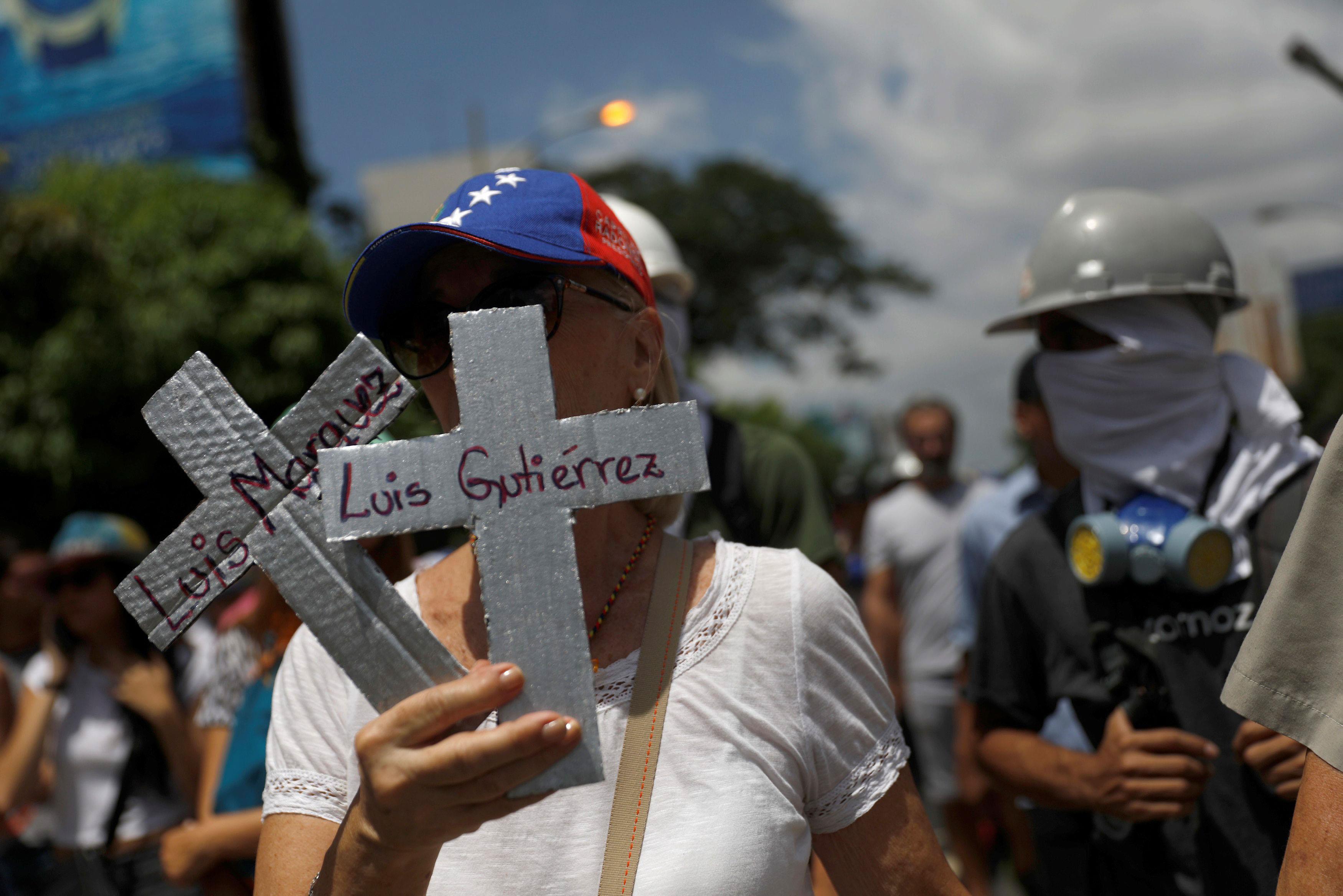Opposition supporters rally against President Nicolas Maduro carrying crosses with the names of vict