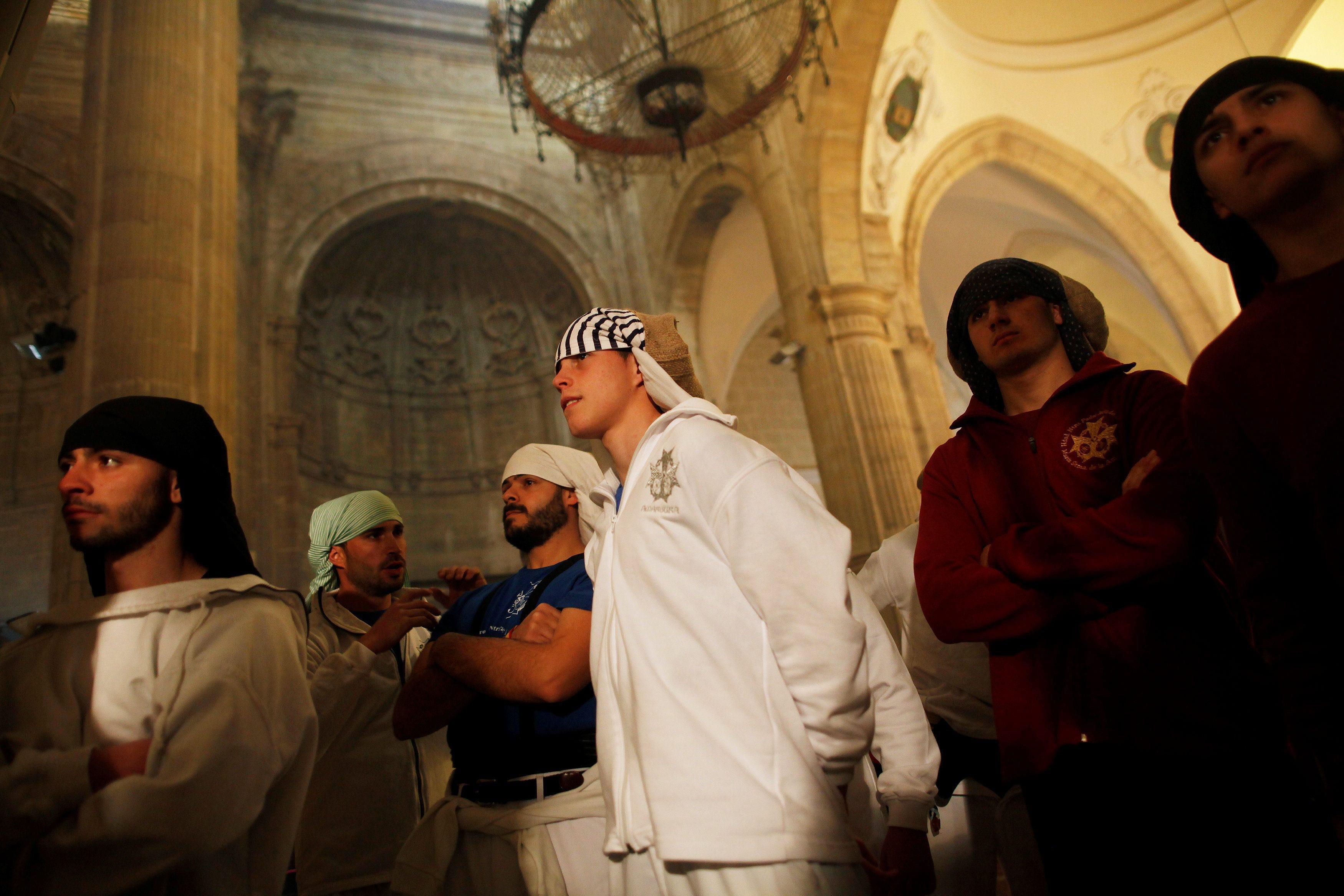 Costaleros watch a statue of Christ inside a church before taking part in a procession during the Ho