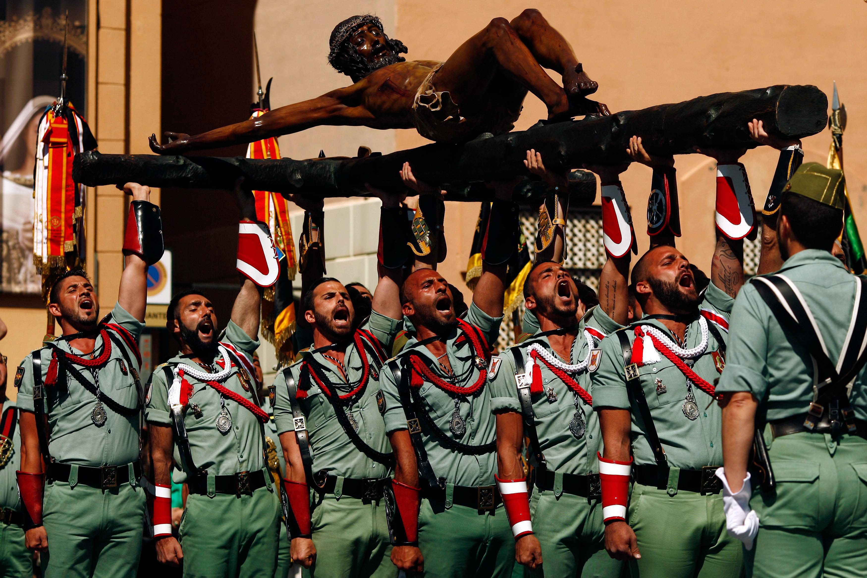 Spanish legionnaires sing an anthem as they carry a statue of the Christ of Mena during a ceremony b