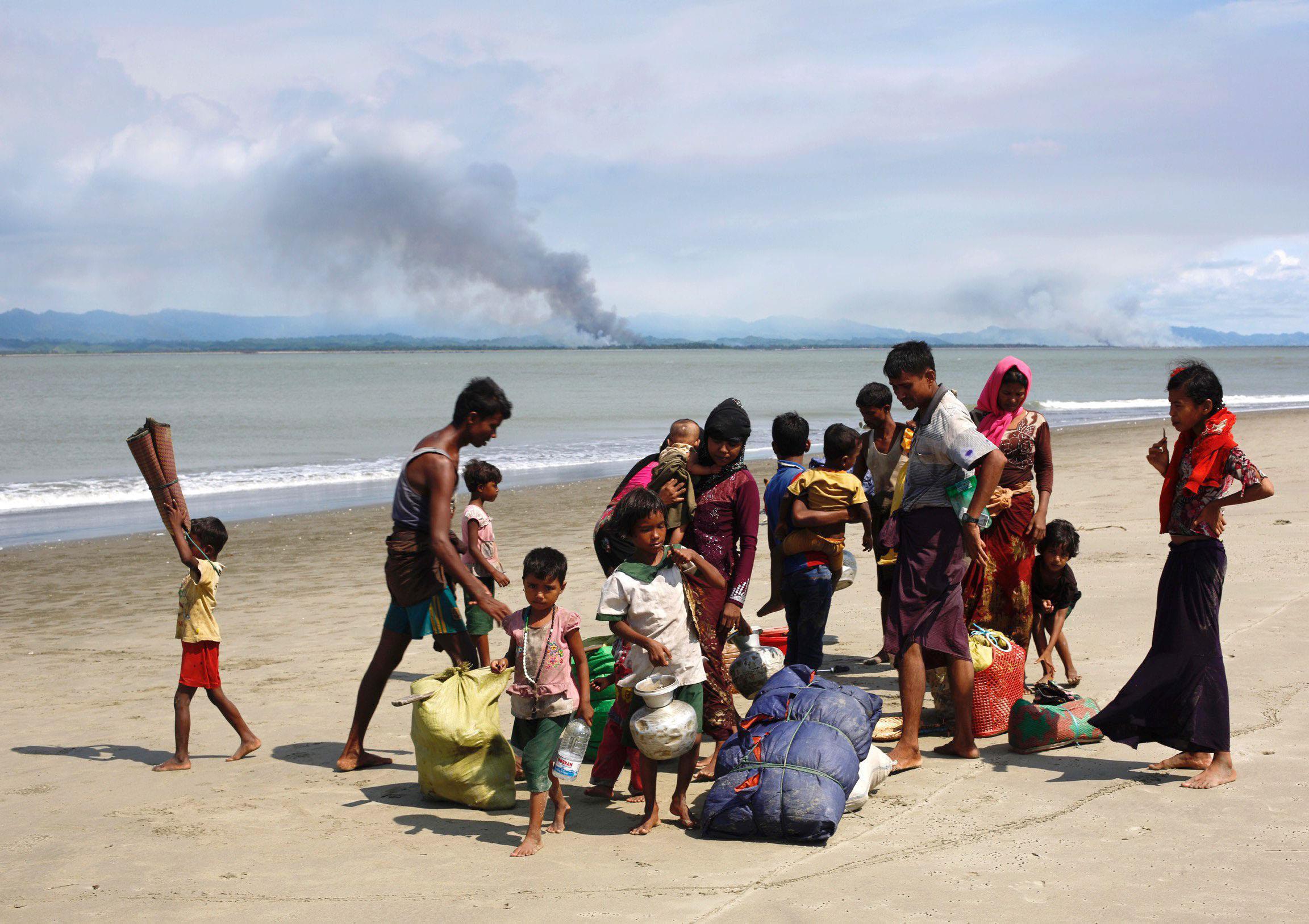 Smoke is seen on Myanmar's side of border as Rohingya refugees collect their belongings on a shore a