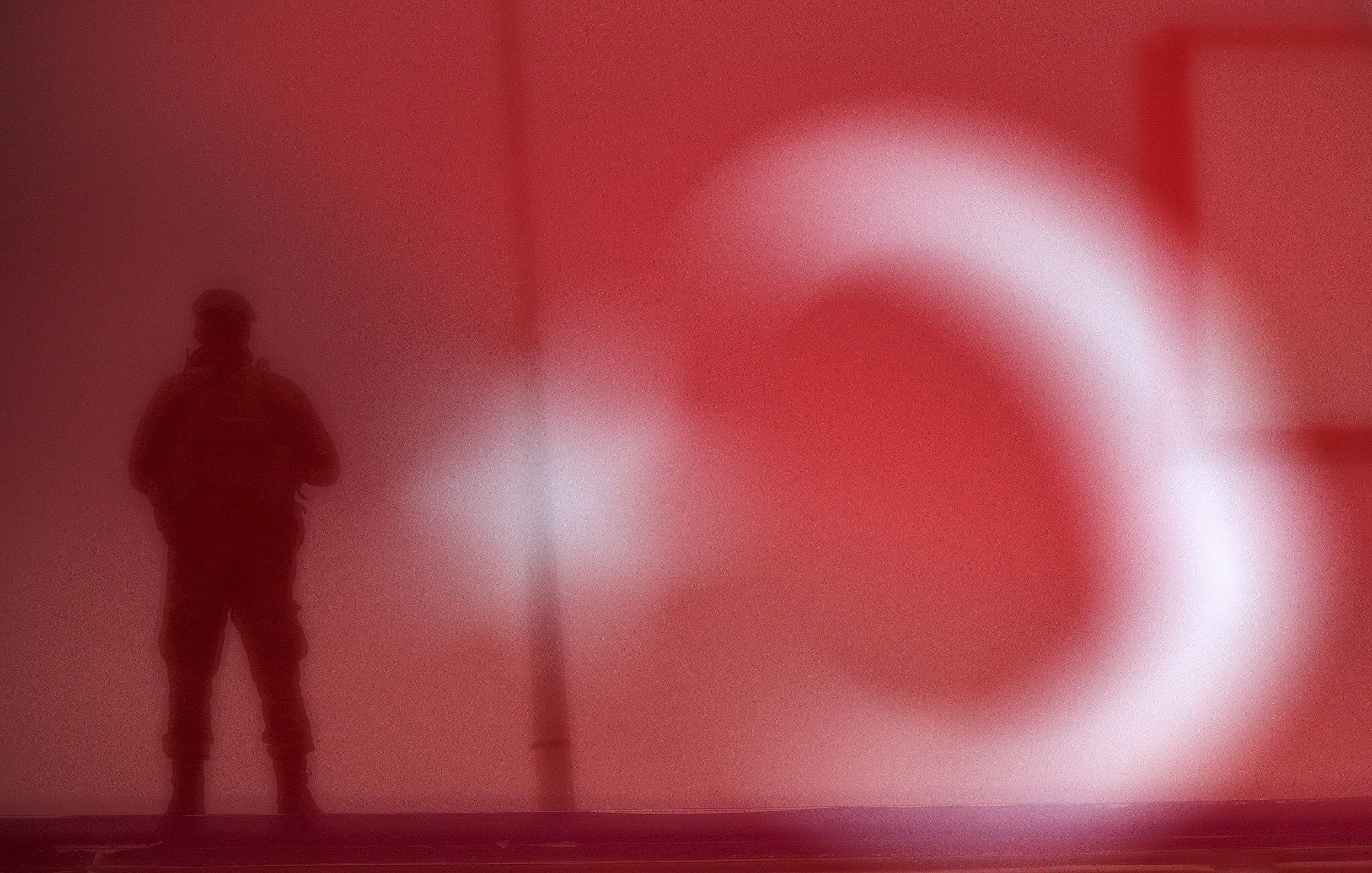 A soldier is seen through a Turkish national flag as he stands guard during an AK Party election ral