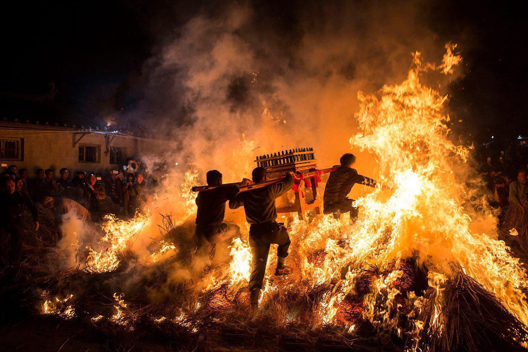 Men carrying a shrine jump over a bon fire, which means a wish for good luck during a traditional Ch