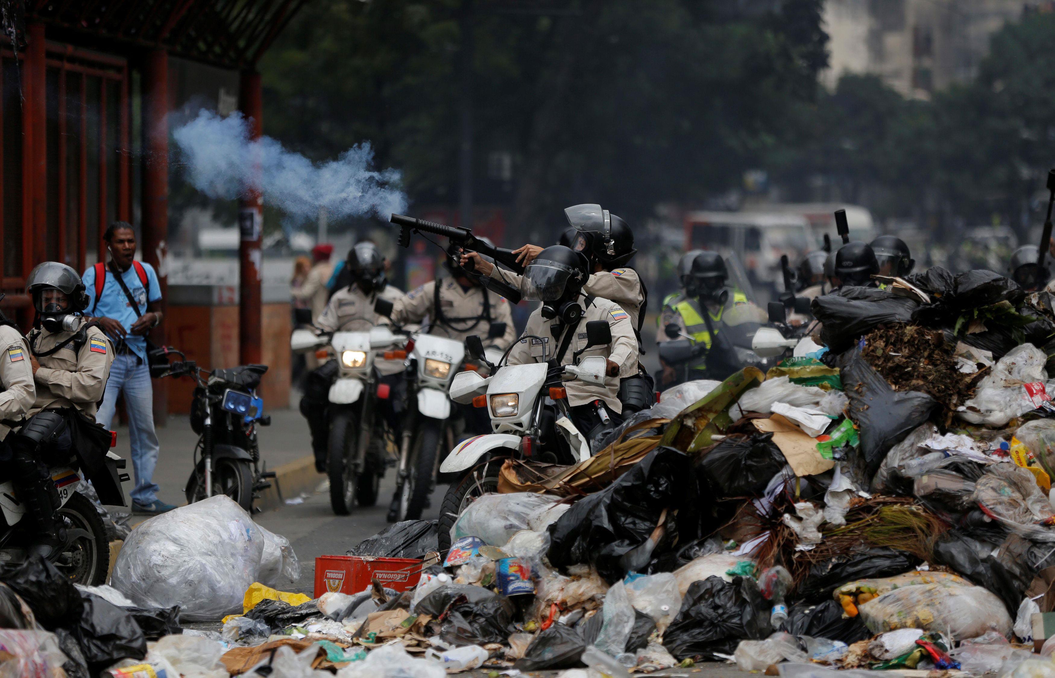 Security forces fire tear gas from behind a pile of garbage during a rally against Venezuelan Presid