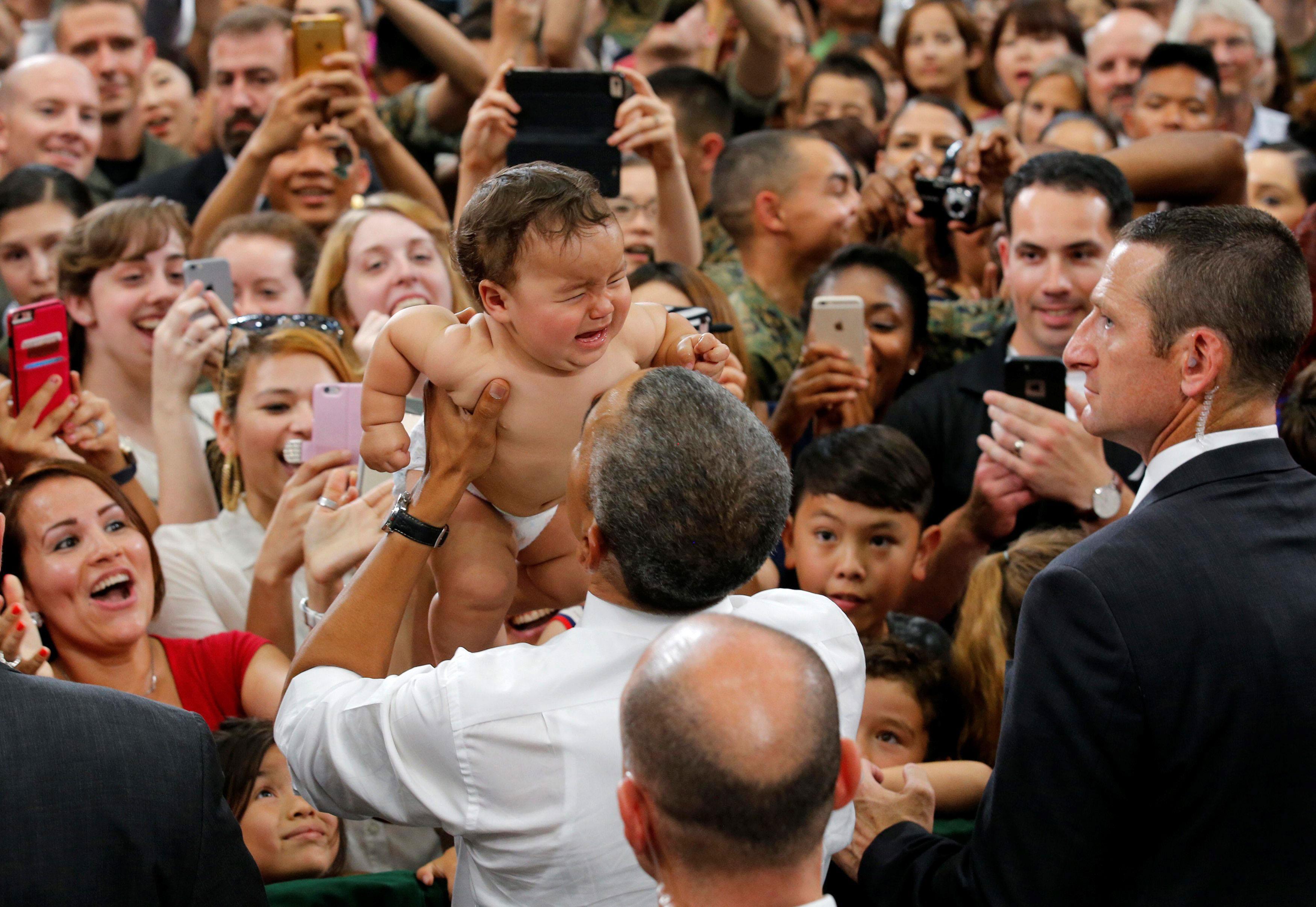A baby cries as U.S. President Barack Obama holds it during visit at Iwakuni Marine Corps Air Statio