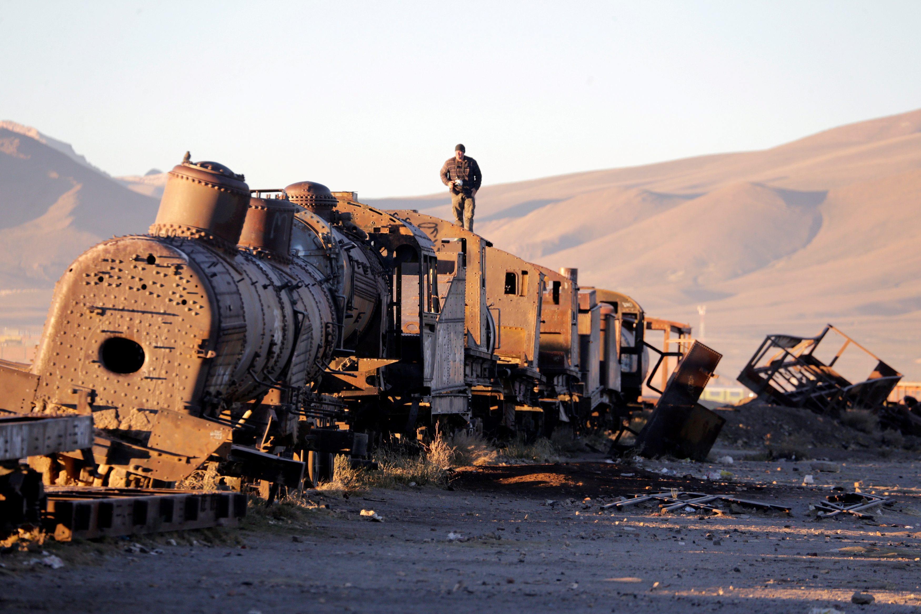 A man stands on an old train of Bolivian Railways Company from 1870-1900 at the train cemetery in Uy