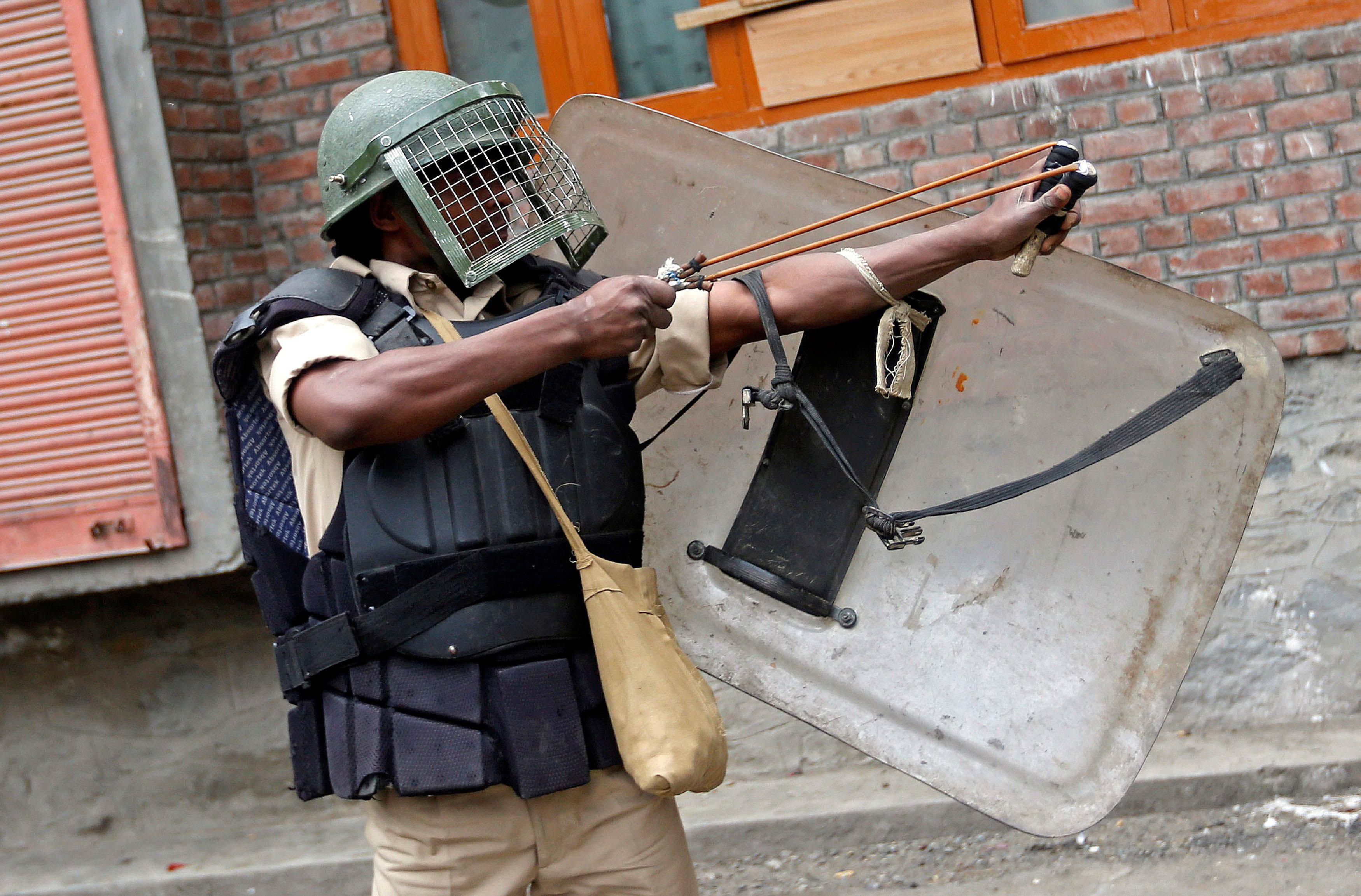 An Indian policeman uses a slingshot during clashes with demonstrators following a protest in Srinag