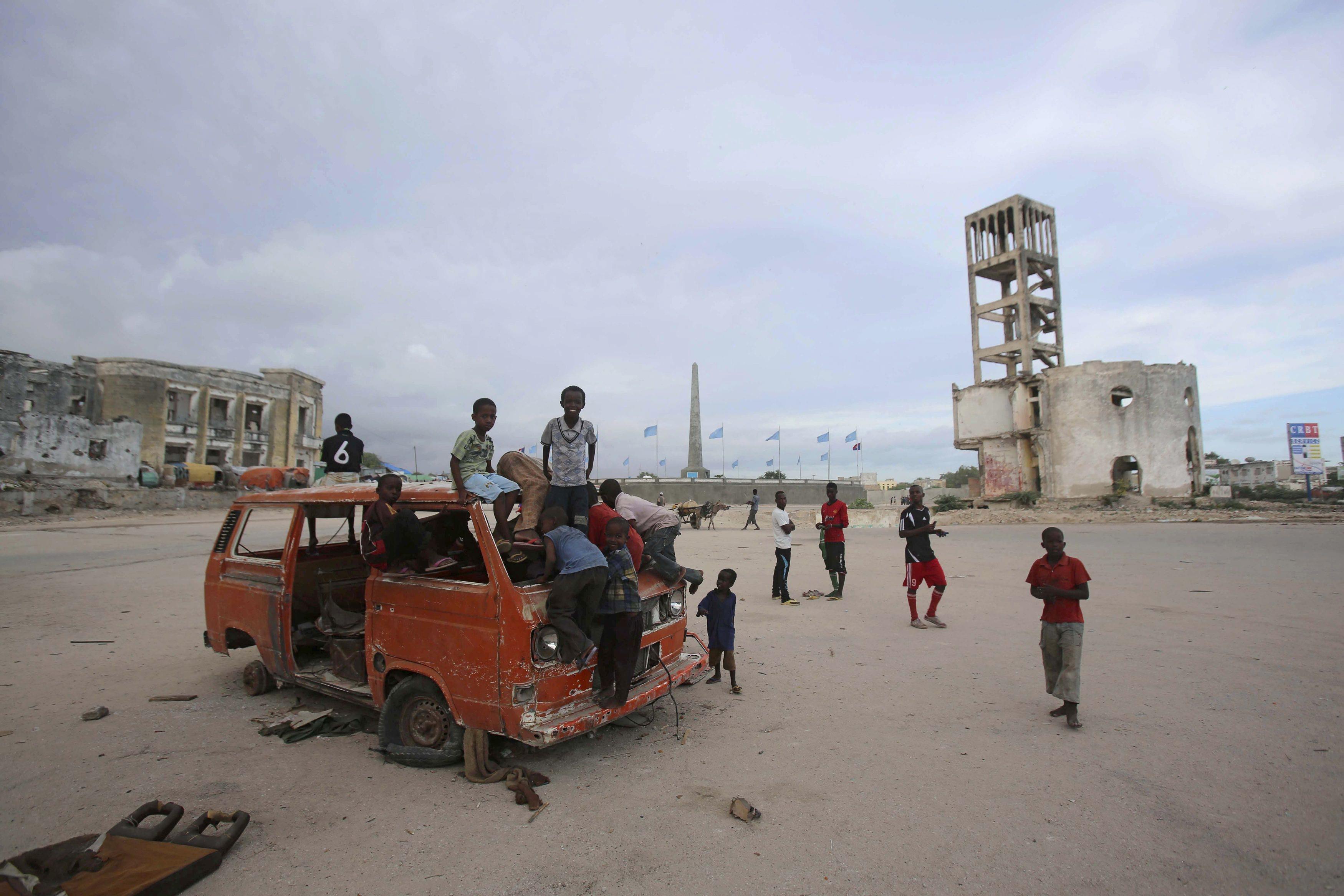 Children play on an abandoned truck in front of the destroyed former parliament building in Mogadish
