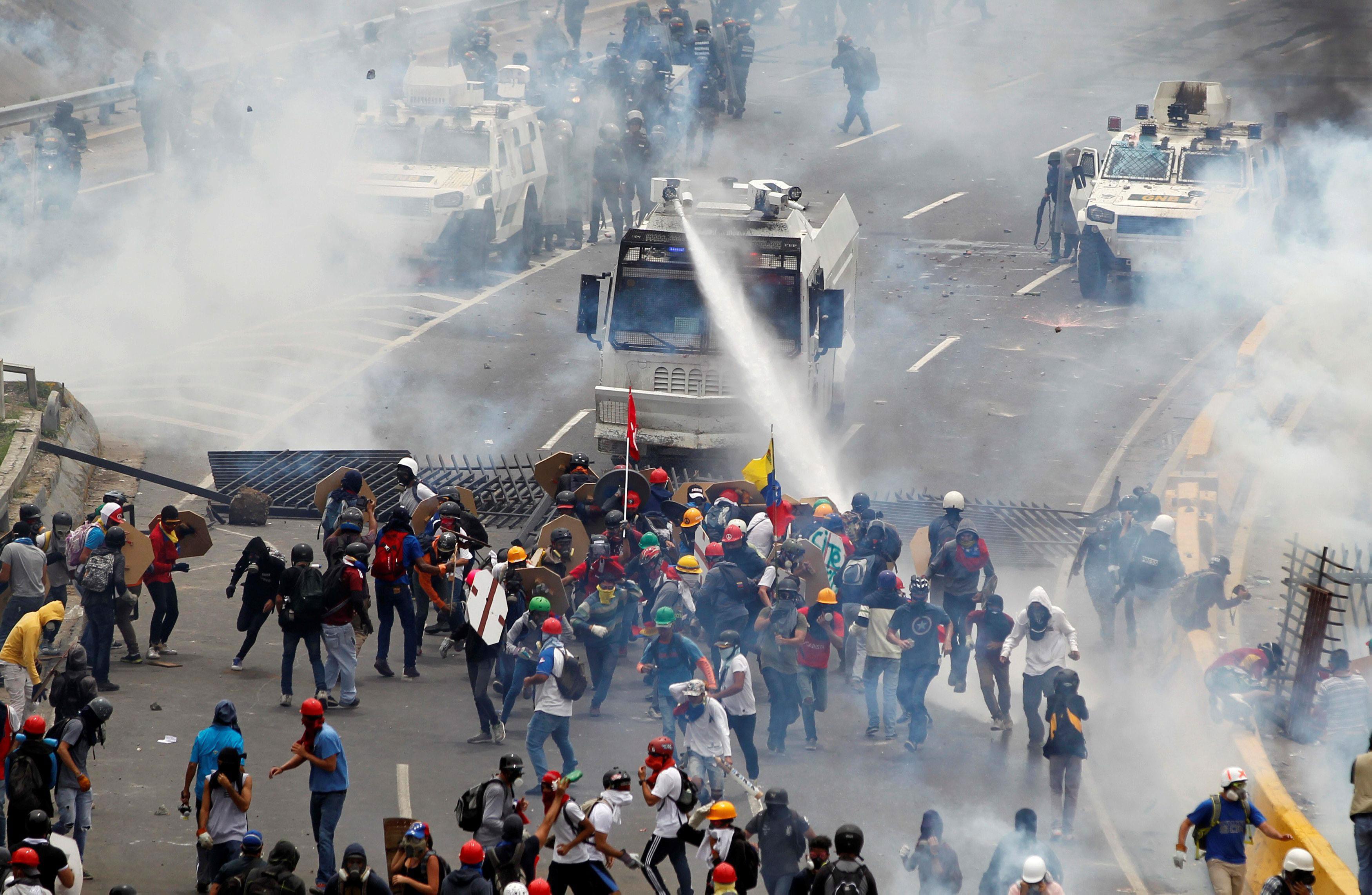 Opposition supporters clash with riot police during a rally against President Nicolas Maduro in Cara