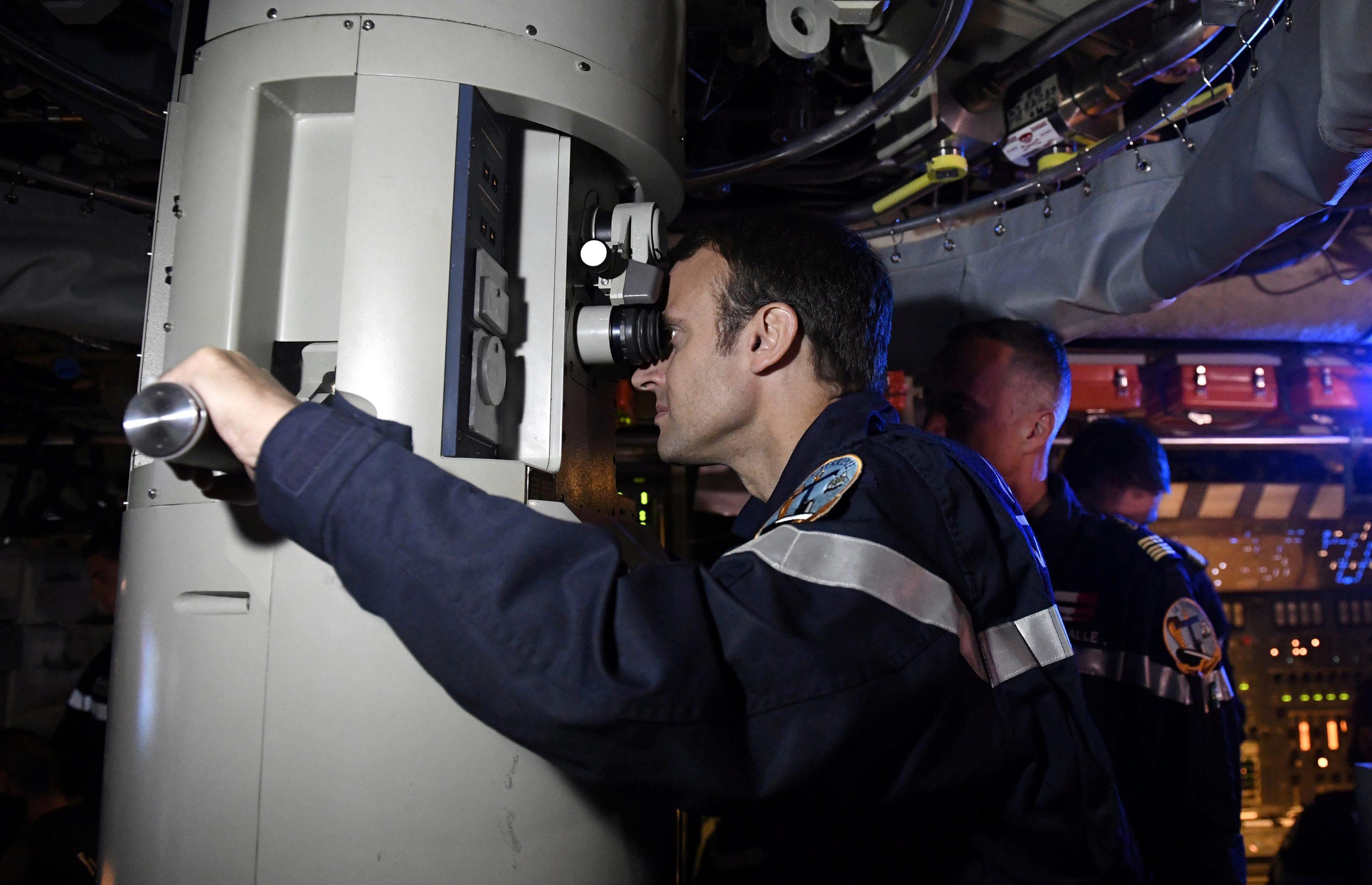 French President Emmanuel Macron looks through the periscope of submarine 