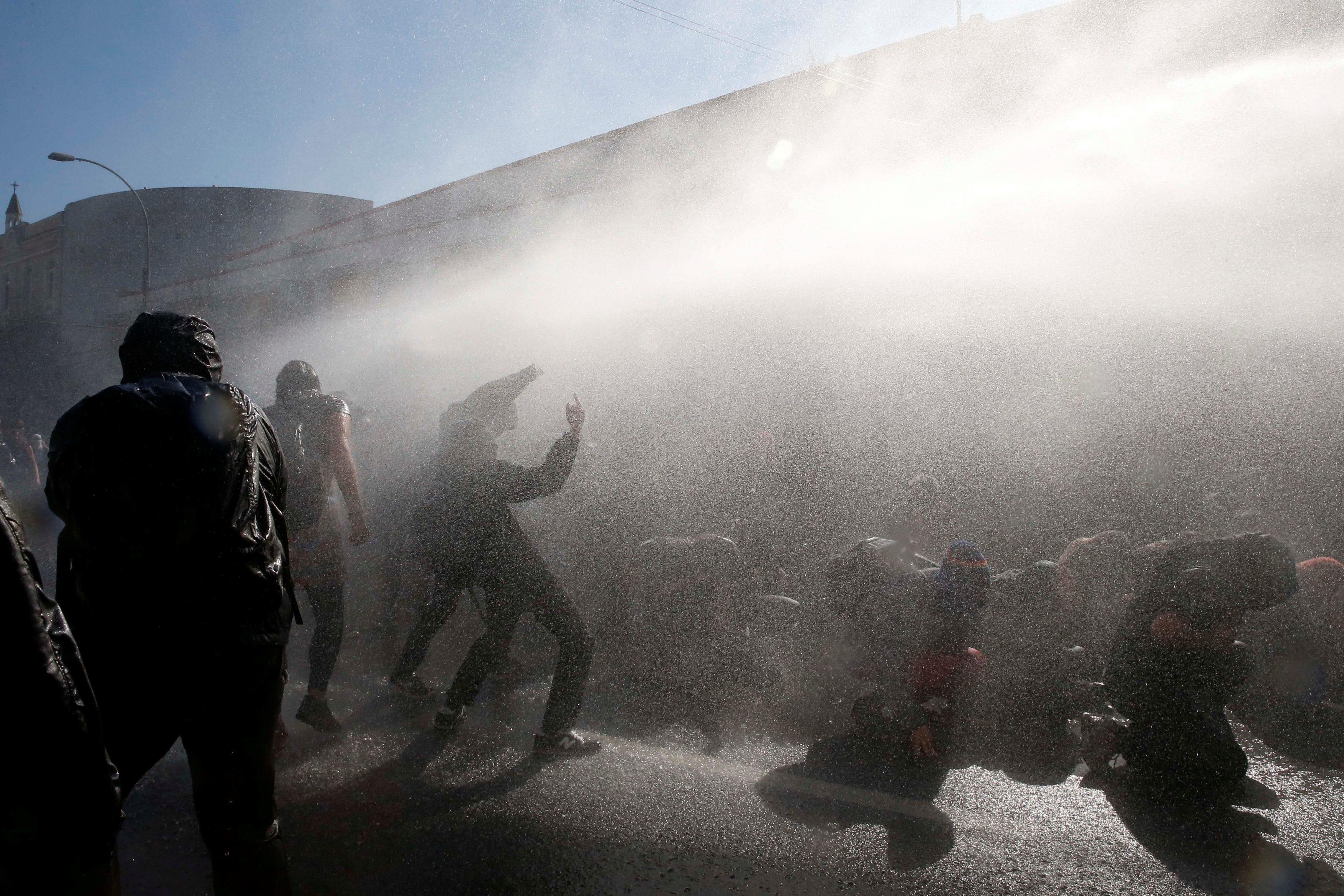A jet of water from a police water cannon is released on demonstrators during an anti government ral