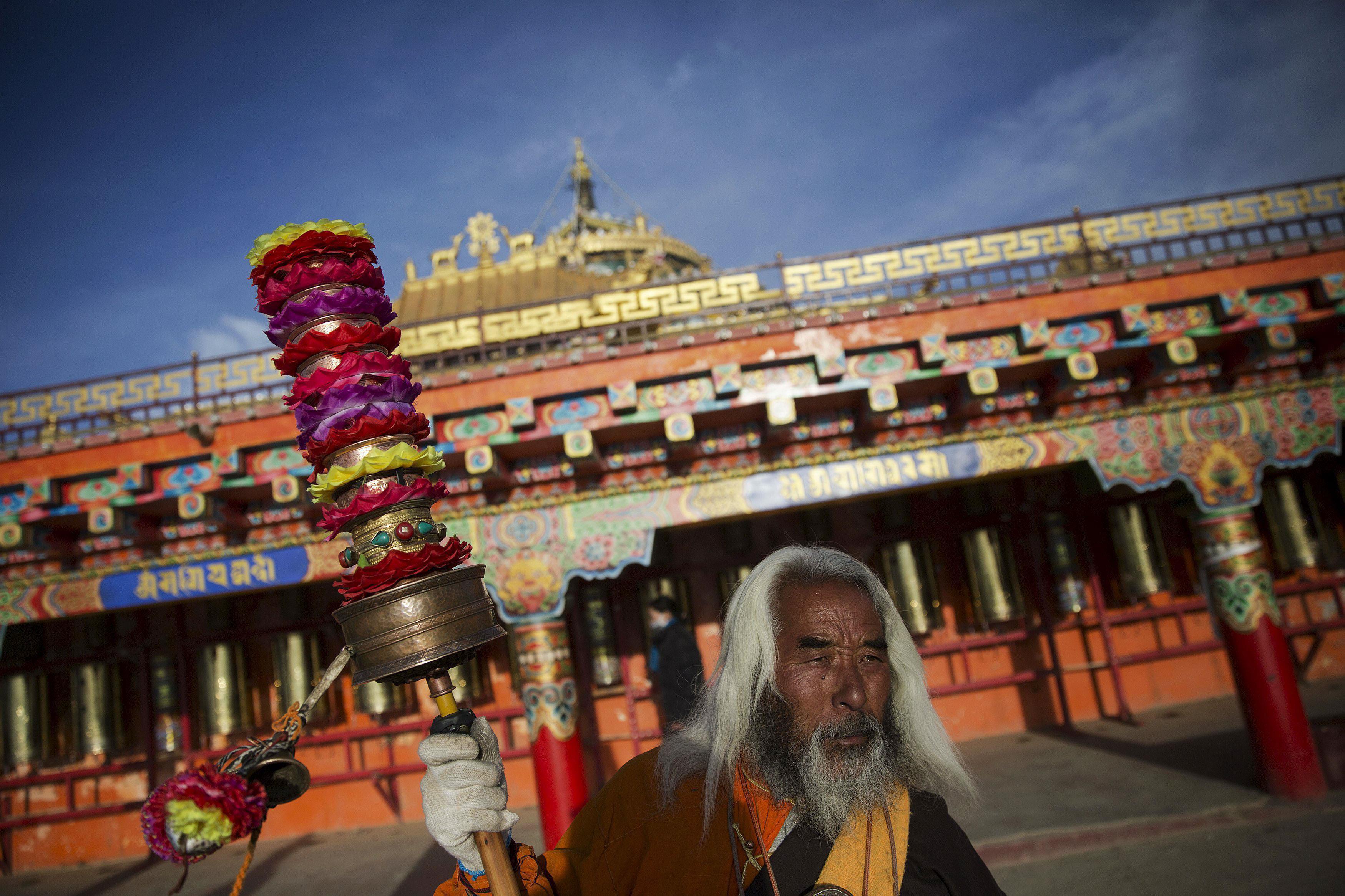 Padma Tsering, a popular Tibetan Buddhist monk spins his prayer wheels at a monastery above the Laru