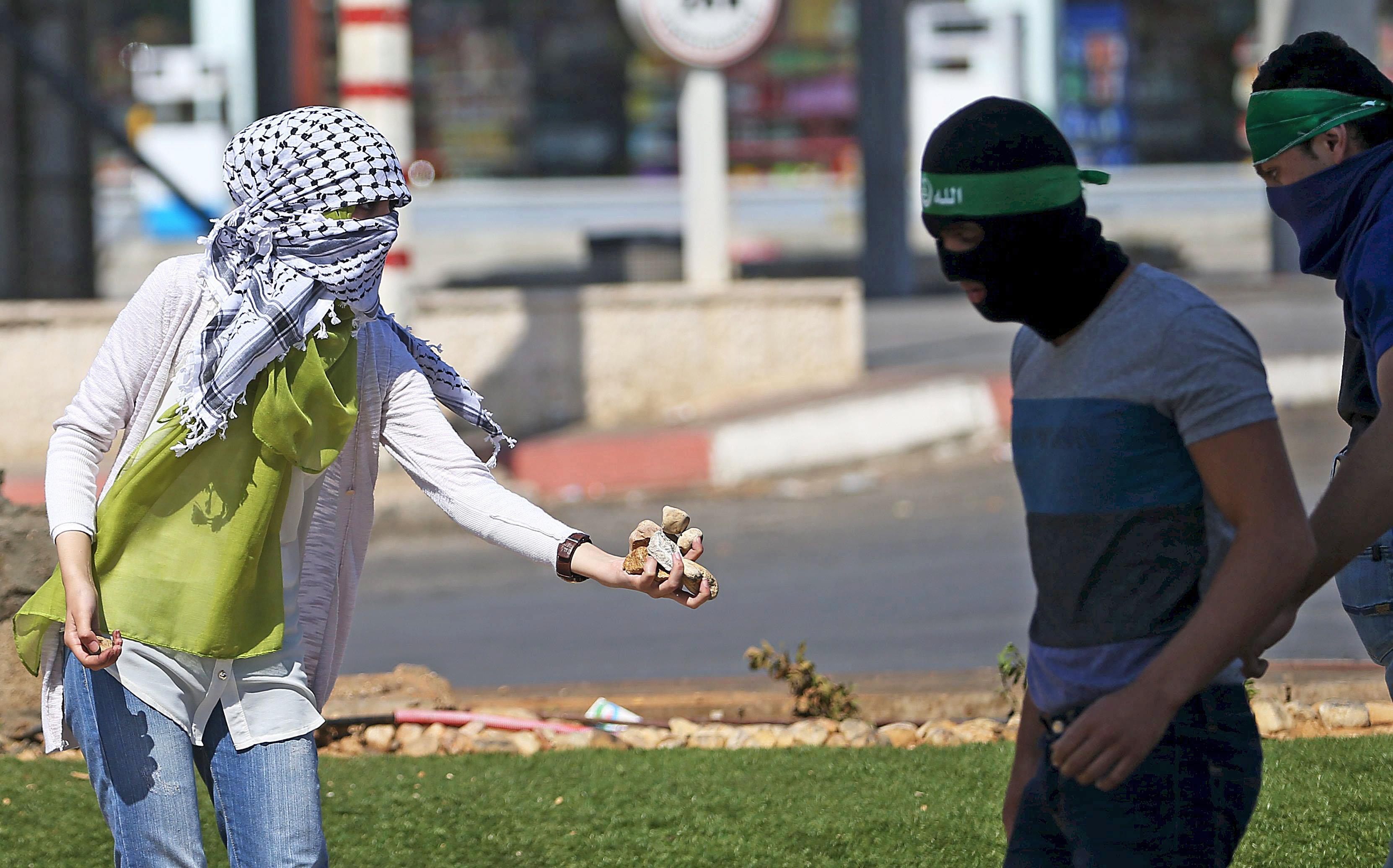 Palestinian girl gives stones to protesters during clashes with Israeli troops near the Jewish settl