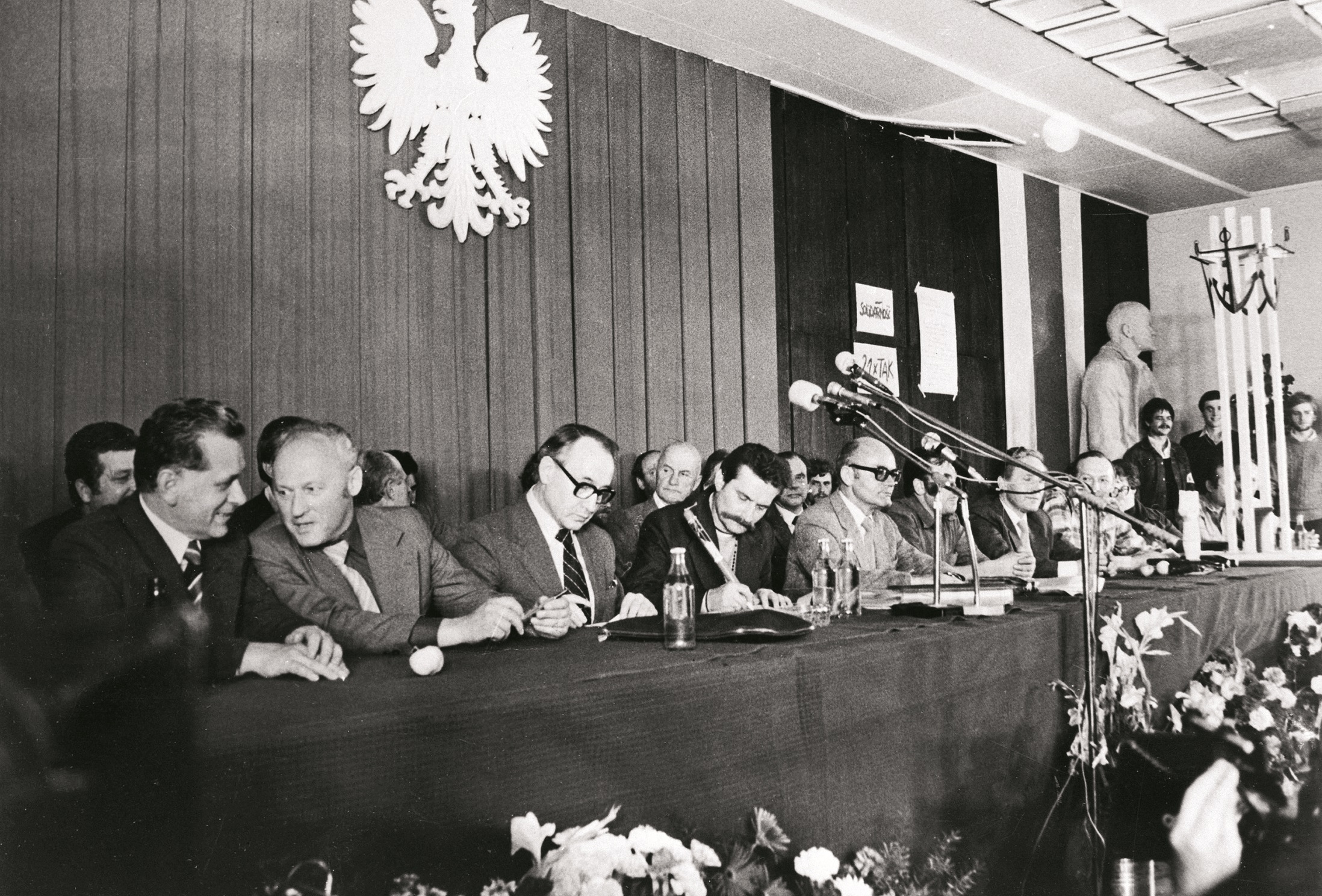 Podpisanie porozumień sierpniowych przez Lecha Wałęsę (czwarty z lewej) i przedstawiciela rządu Mieczysława Jagielskiego (trzeci z lewej), Sala BHP Stoczni Gdańskiej, 31 sierpnia 1980 r.