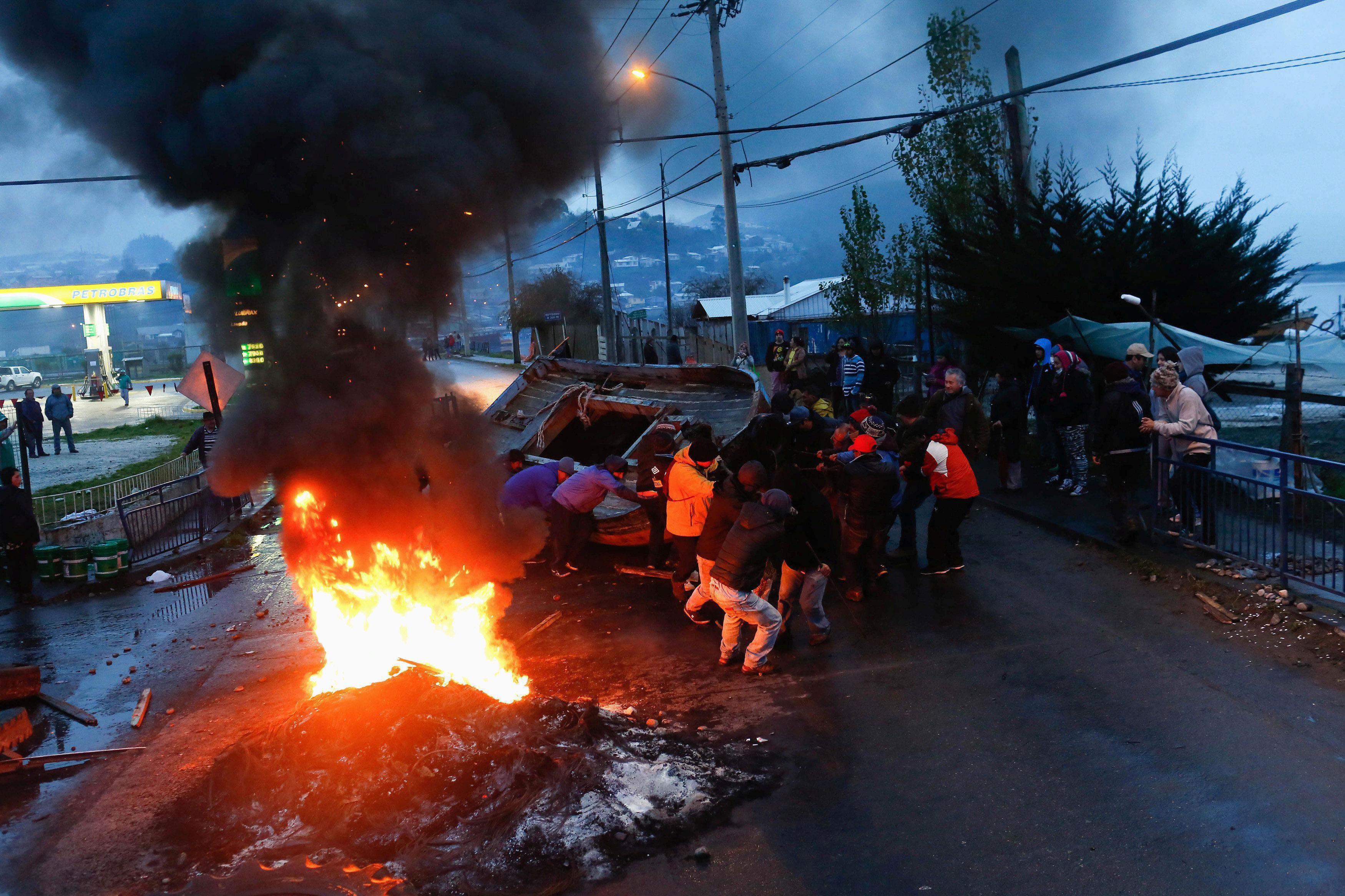 Fishermen block a road with a boat during a protest calling on the government to help ease the econo