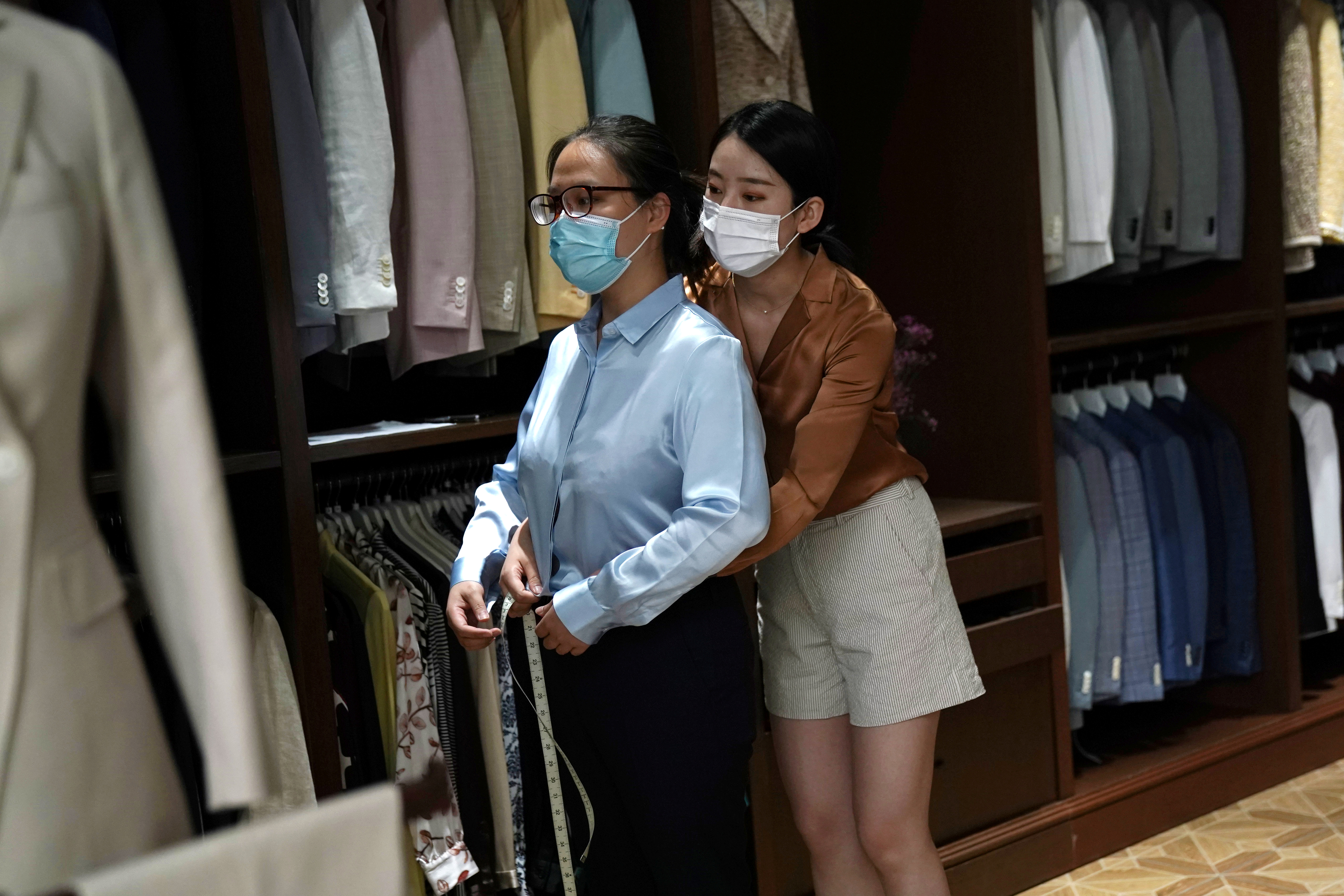Ekspedientka obsługująca klientkę w zakładzie krawieckim w biznesowej części Pekinu, gdzie ubrania są szyte na specjalne zamówienie.