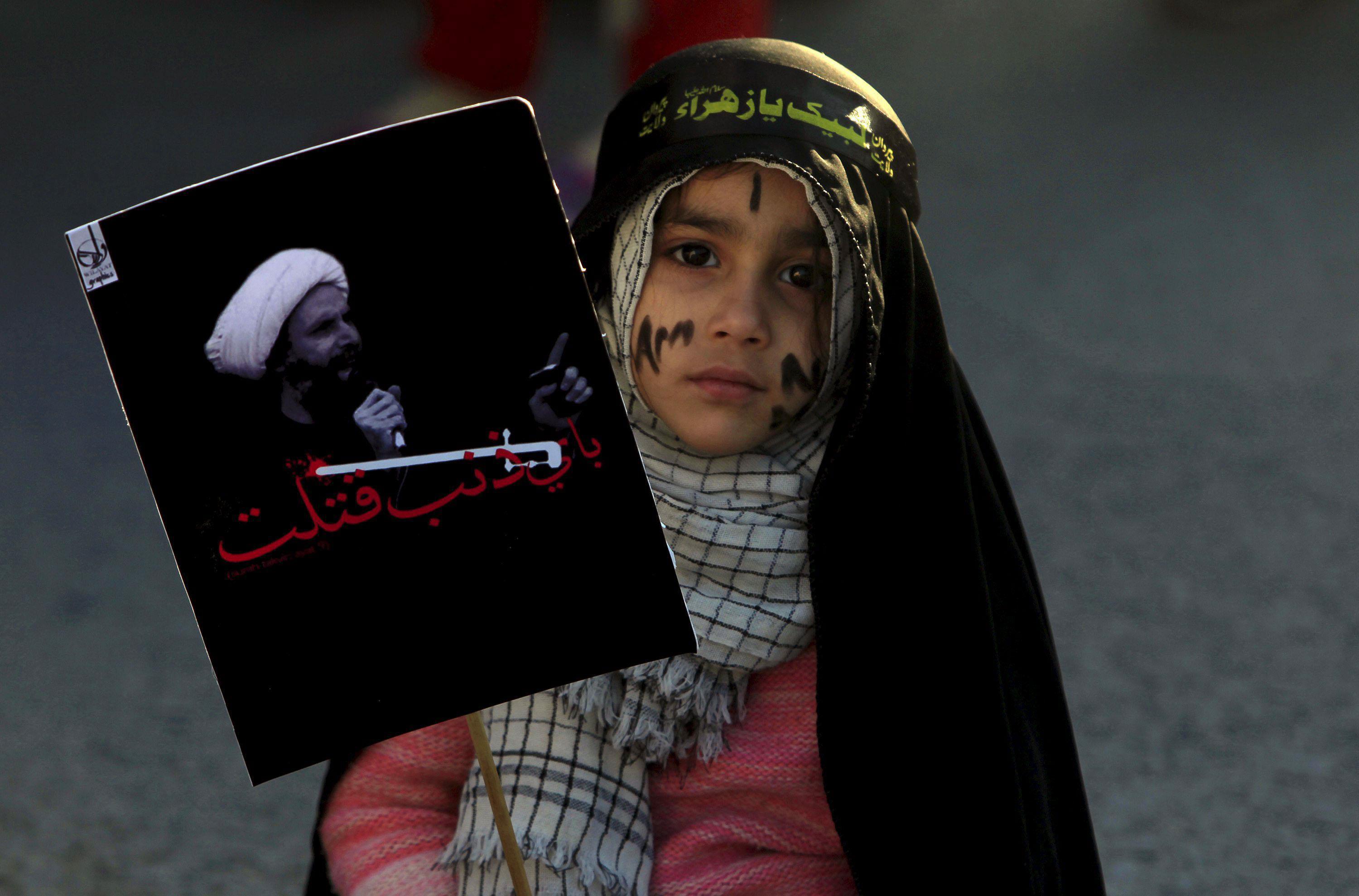 A Shi'ite Muslim girl holds a picture of Shi'ite Muslim cleric Nimr al-Nimr as she takes part in a p