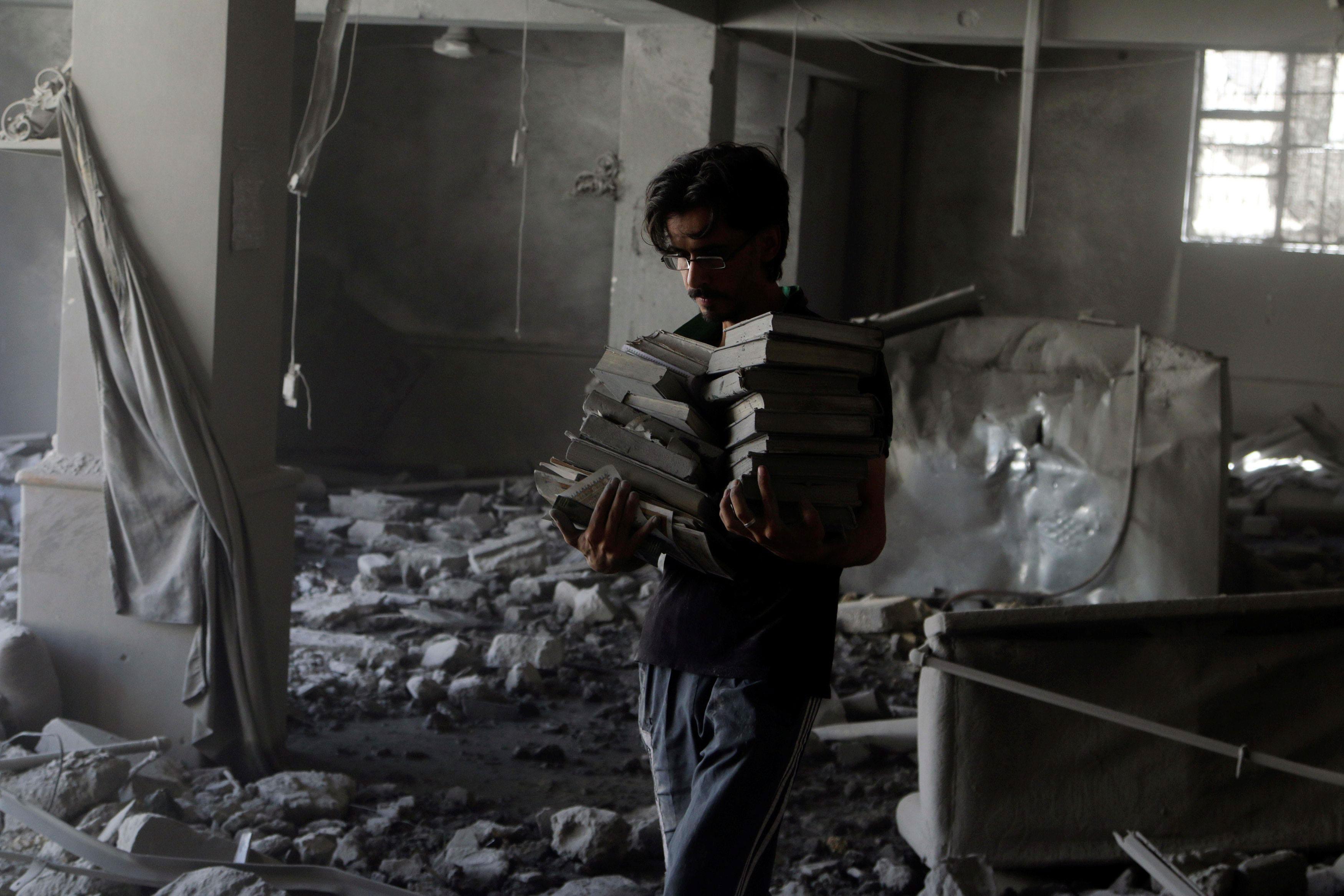A man carries Koran books he collected amid damage inside al-Aqsa mosque after an airstrike on the r