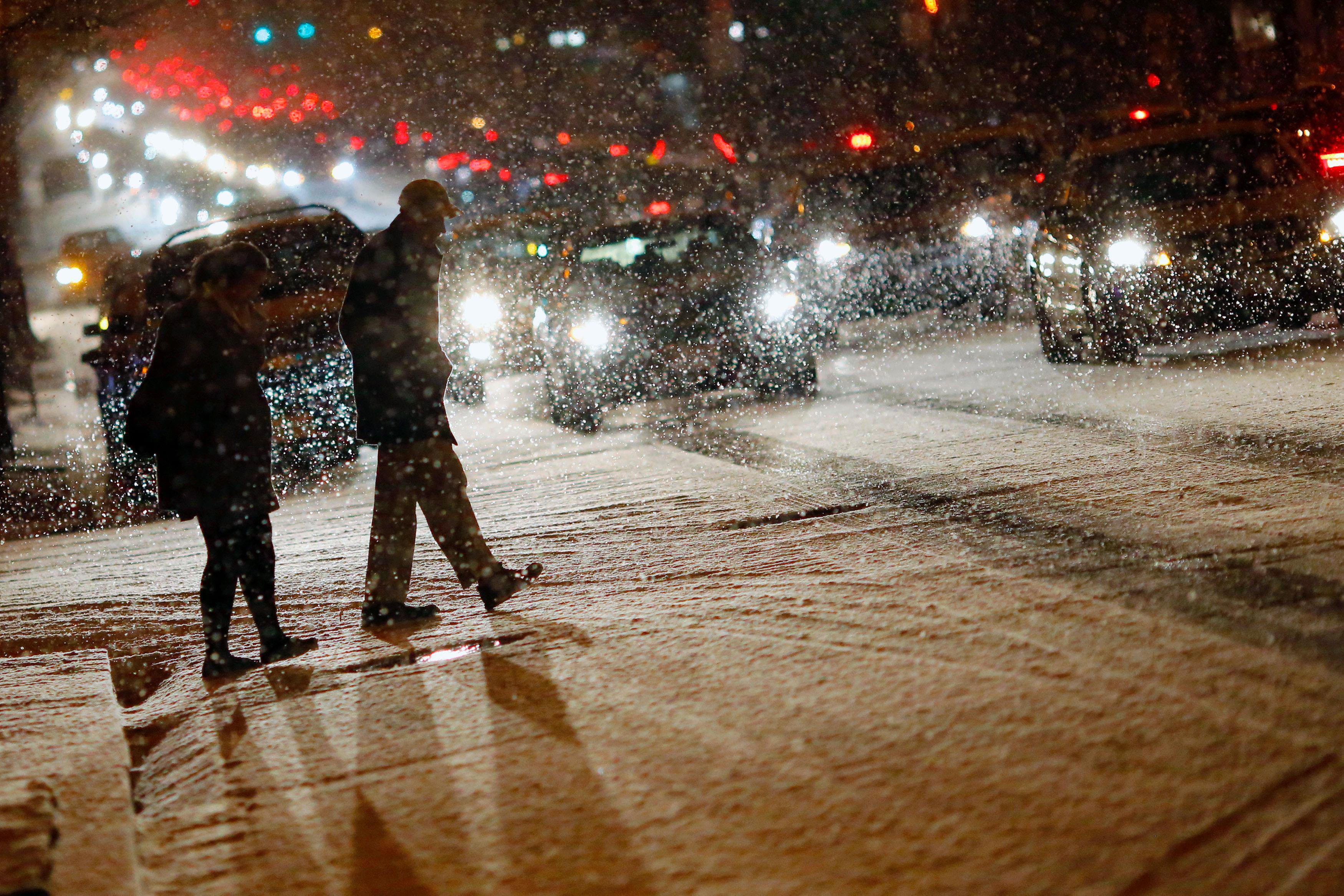 People cross a street as it snows in Washington
