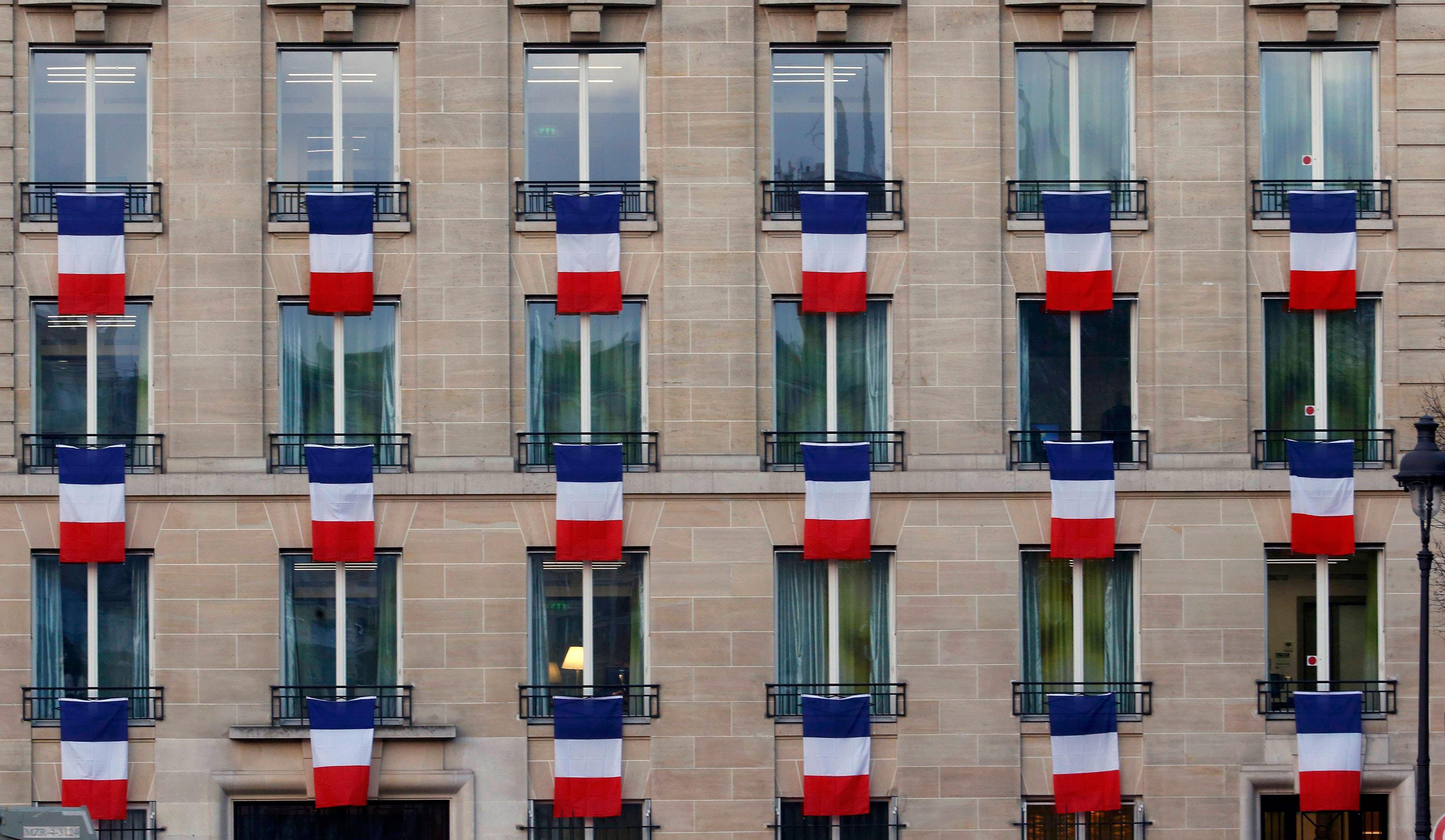 French flags hang from windows of a building near the Invalides in Paris to pay tribute to the victi