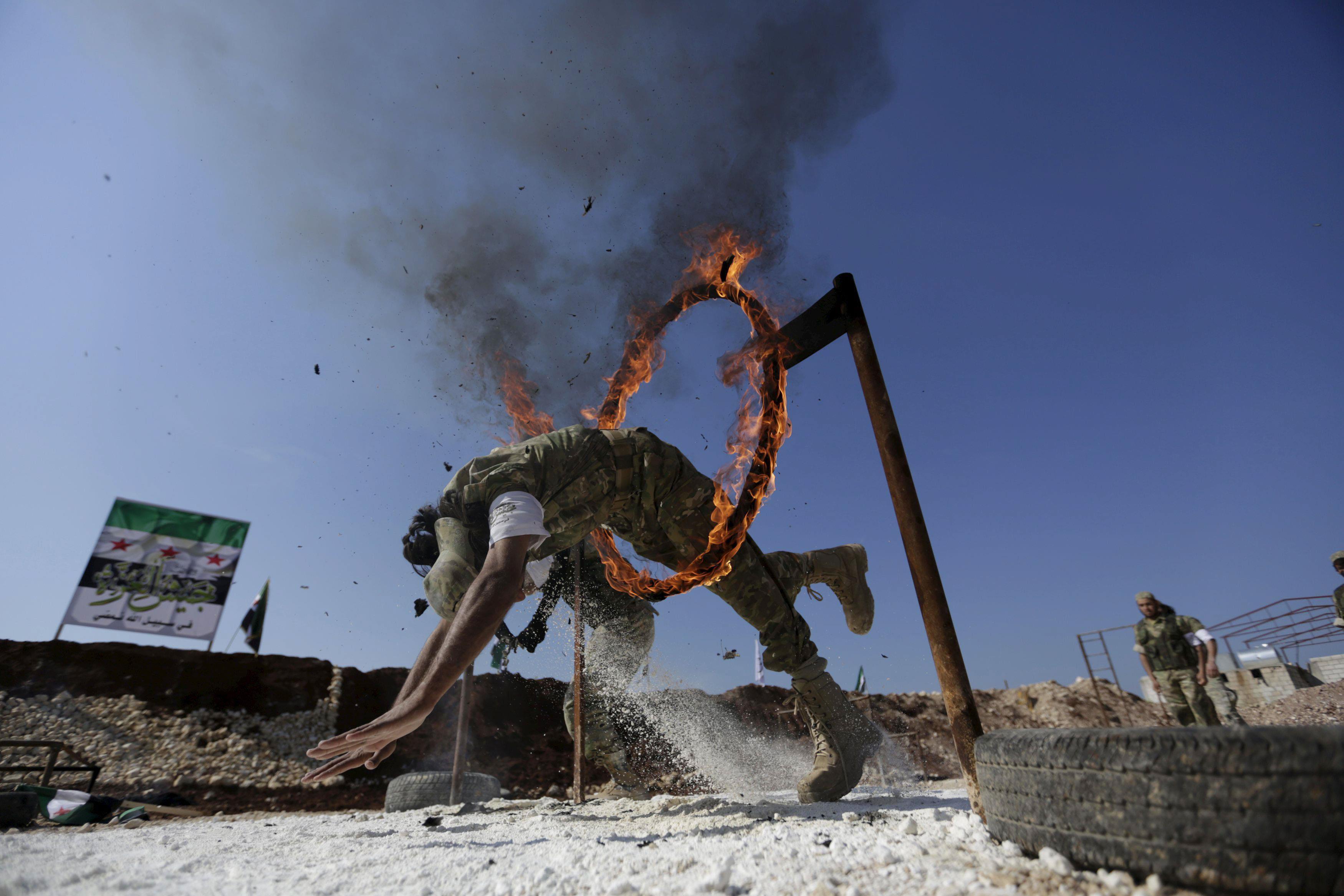 A rebel fighter jumps through a fire loop as he demonstrates his skill during a military display as 
