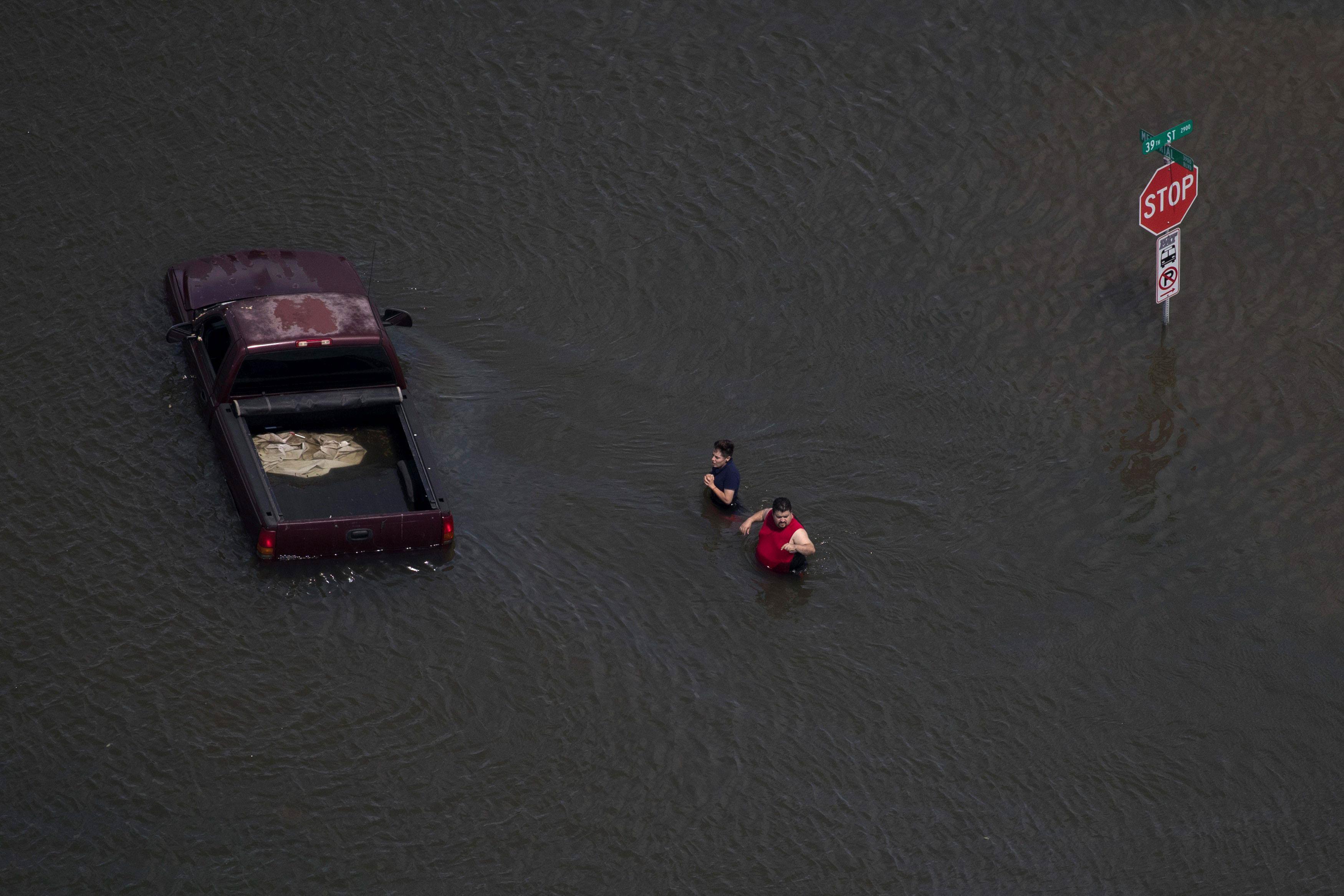 A woman holds her hands as she and a man stand submerged in flood waters caused by Tropical Storm Ha