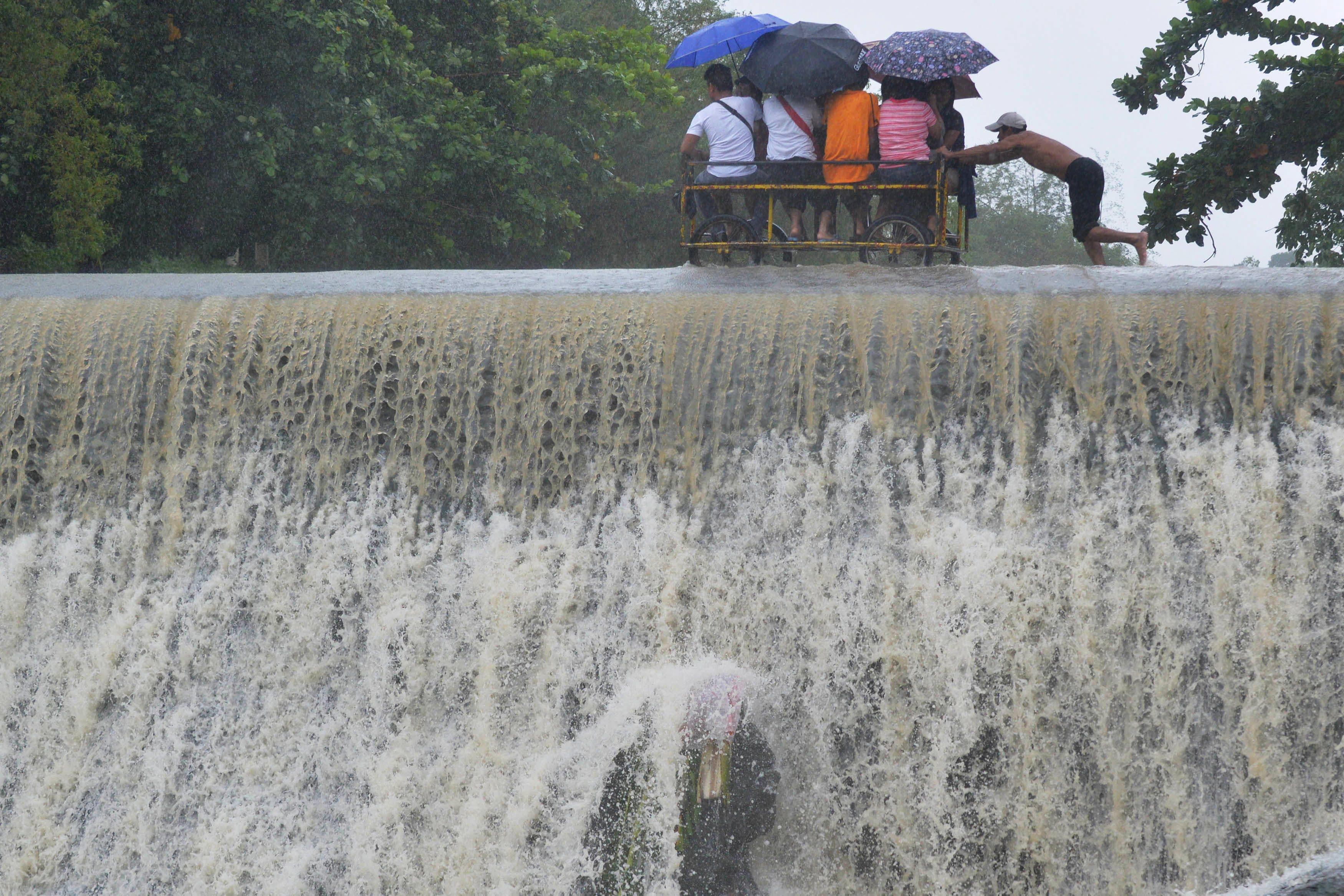 Residents cross a swelling dam, due to rising waters brought about by Typhoon Koppu, in Las Pinas ci