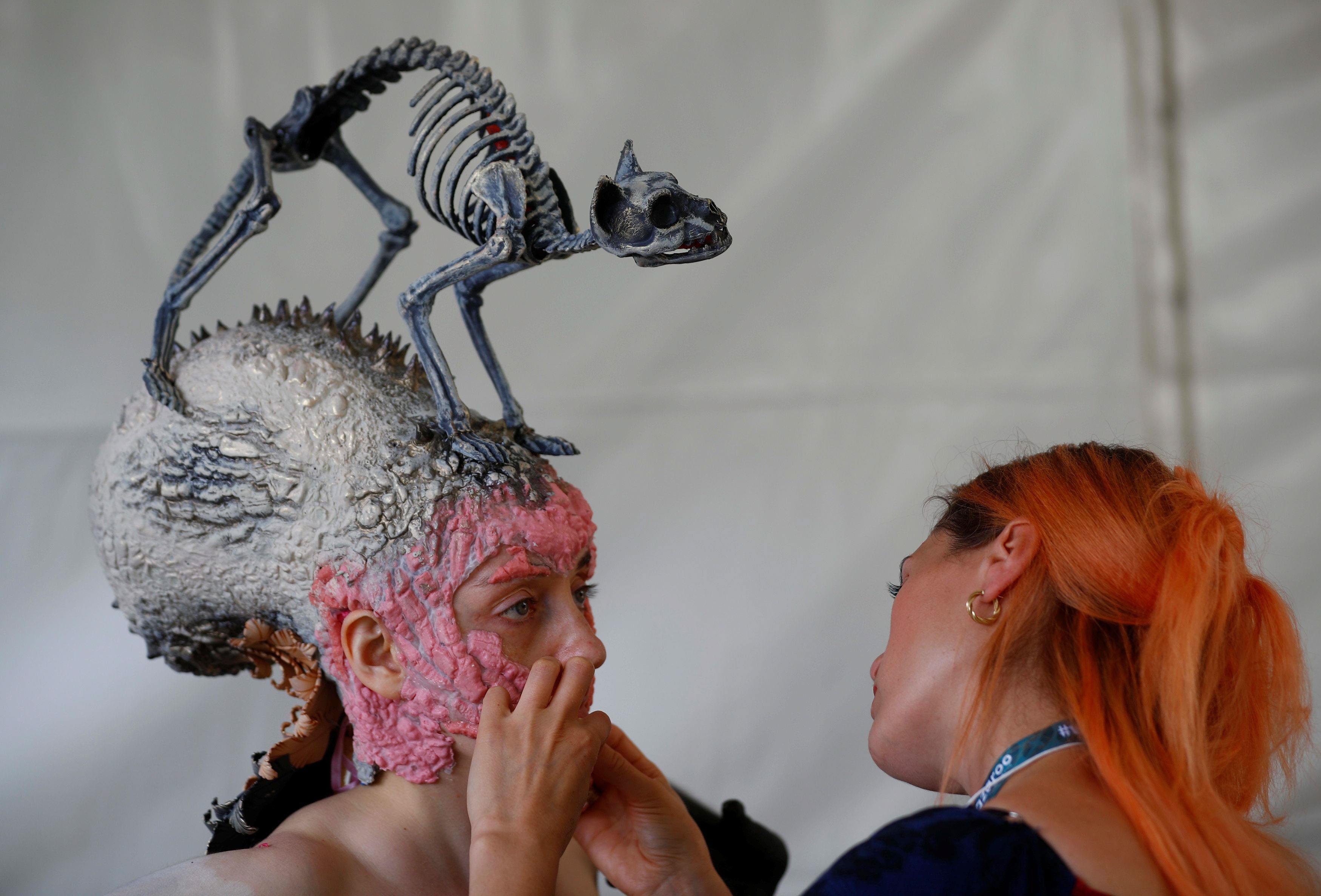 An artist touches up makeup on a model during the 