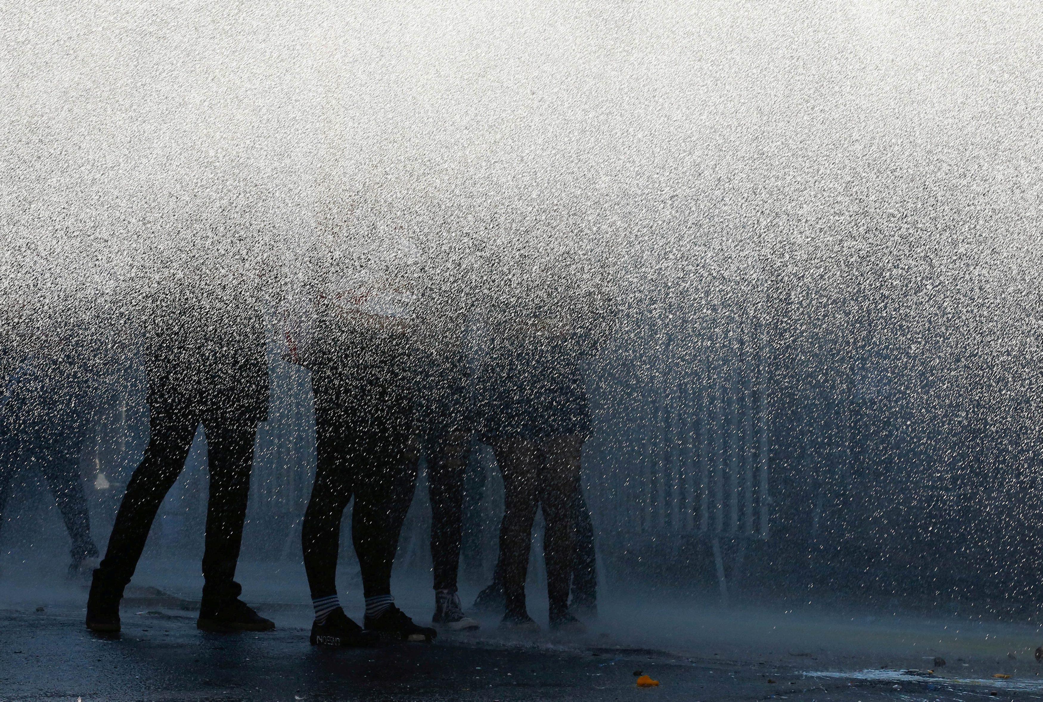 Demonstrators are hit by water cannon used by riot police during a rally demanding an end to sexism 