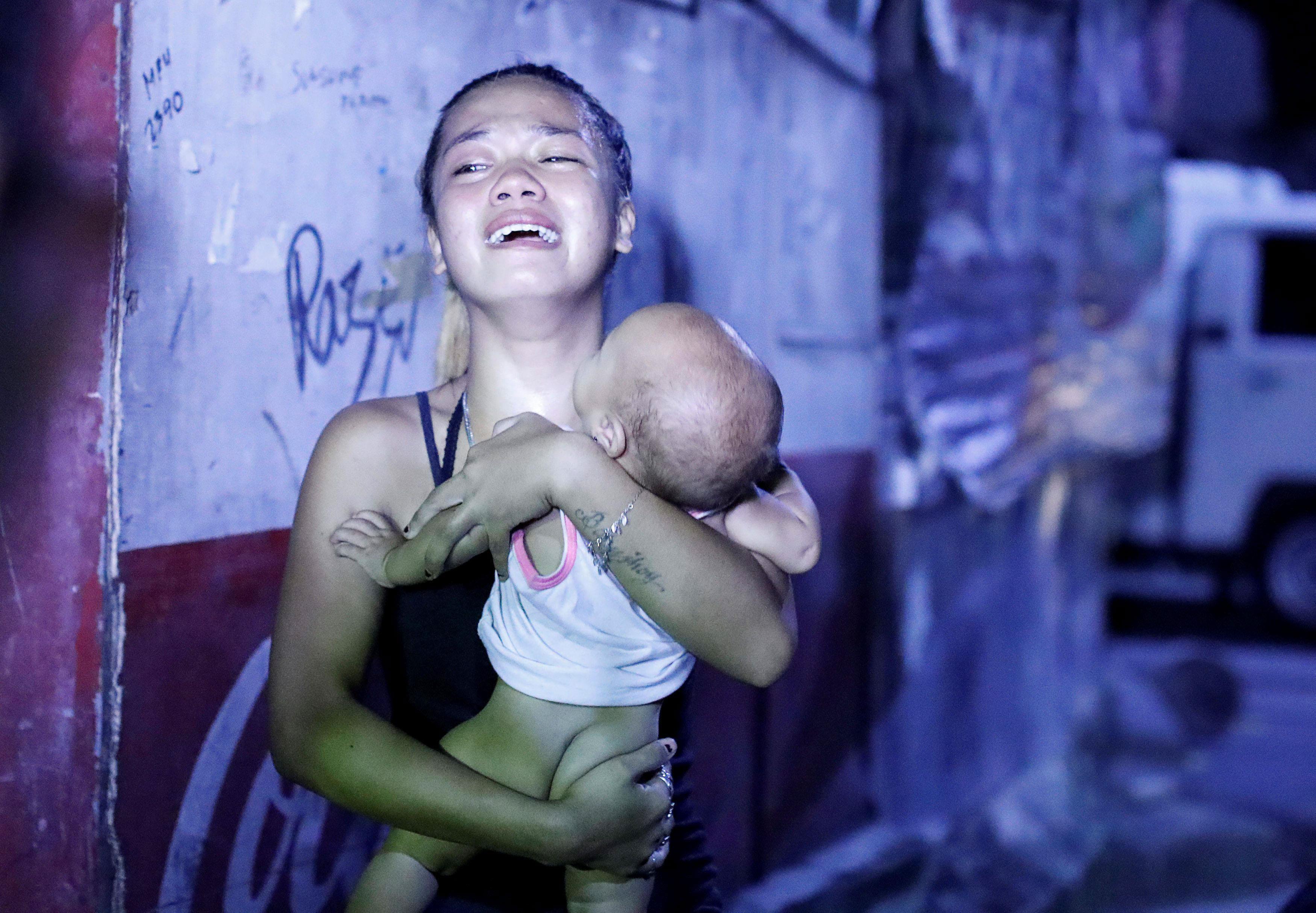 A woman cries as she carries her baby after her husband was among those killed during anti-drug oper