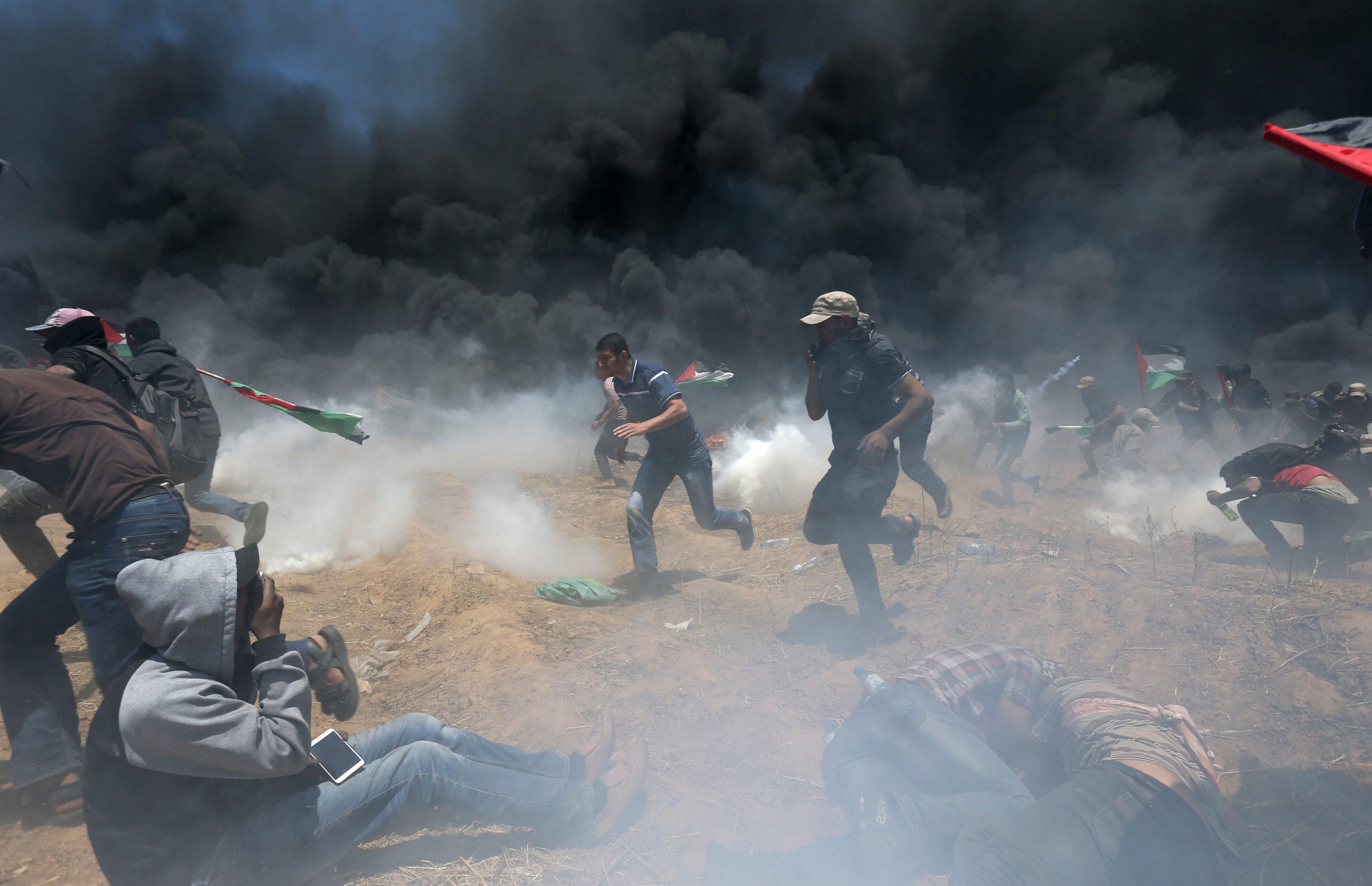 Palestinian demonstrators run for cover from Israeli fire and tear gas during a protest against U.S.
