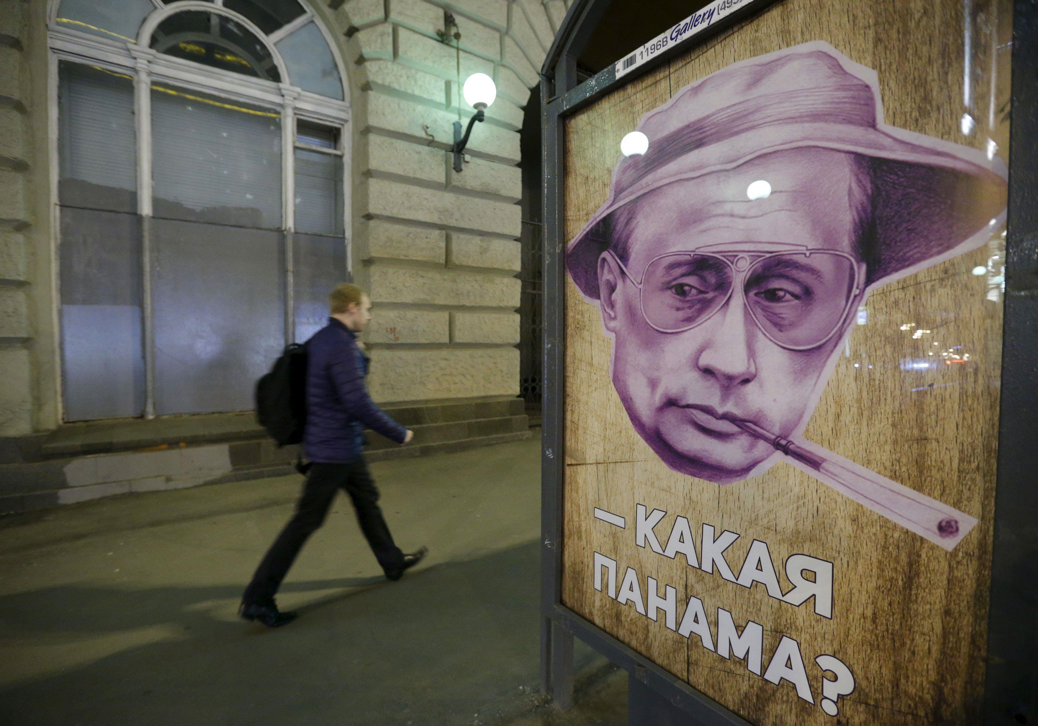 Man walks past poster depicting Russian President Putin at bus stop in Moscow