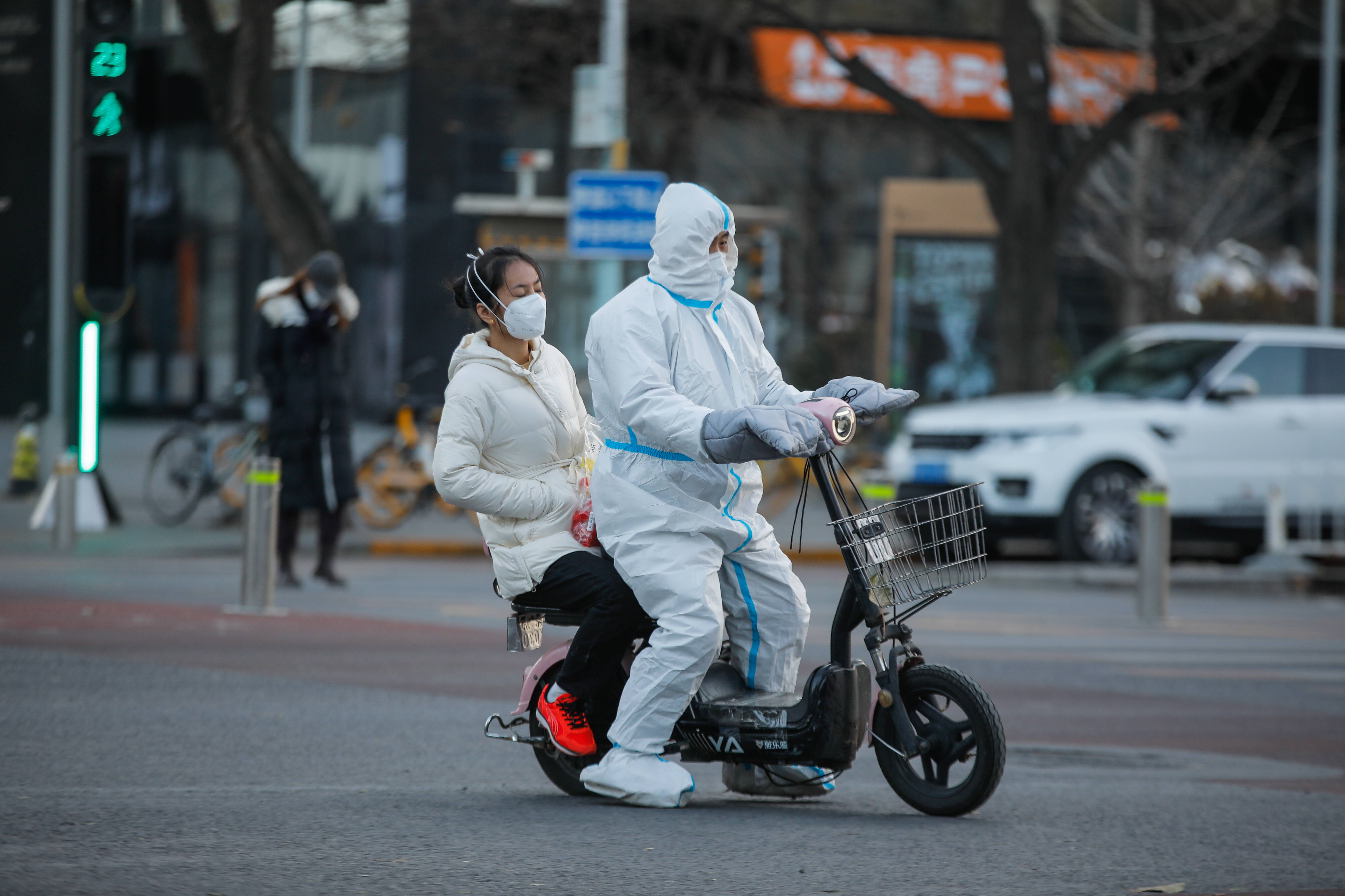 Wolontariusz chińskiej służby zdrowia przemierza na skuterze pekińskie ulice.