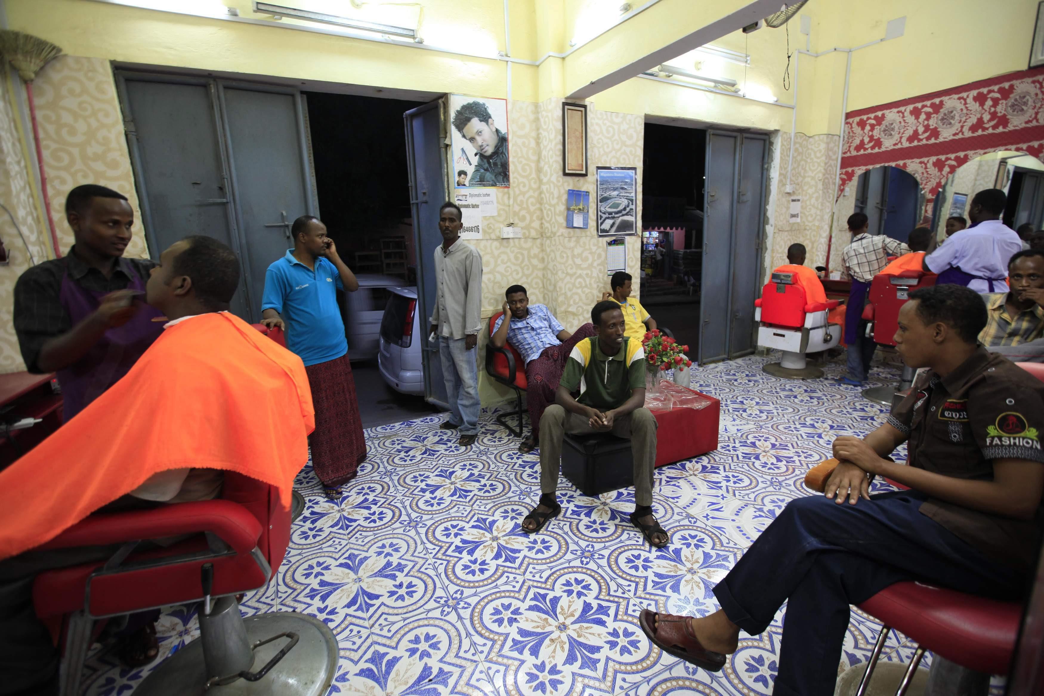 Men receive haircuts at a barber shop in Mogadishu October 3, 2013. Street lamps now brighten some o