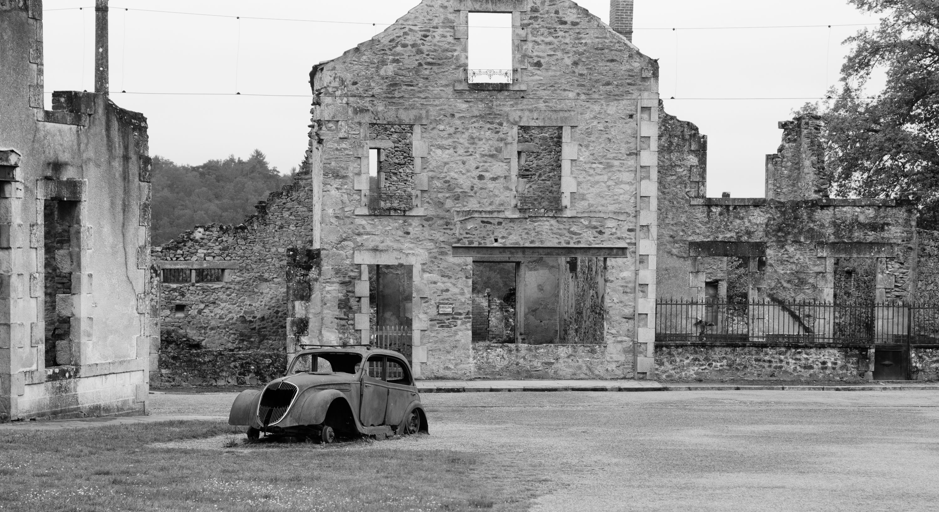 Tragedia rozegrała się <B>10 czerwca 1944 roku</B>. Oddziały SS w odwecie za zabicie przez francuski ruch oporu oficera SS weszły do miasteczka, wyganiając mieszkańców z domów i <B>rozstrzeliwując wszystkich bez wyjątku - mężczyzn, kobiety i dzieci</B>. <BR><BR> Tych, którzy nie zginęli od razu, Niemcy zapędzili do kościoła. Budynek <b>podpalili, wrzucali do środka granaty, strzelali do osób, które próbowały uciec</b>. Tego dnia wymordowali <b>642 mieszkańców miasteczka</b>. Przeżyła 47-letnia kobieta, której udało się wyskoczyć przez okienko w kościele i uciec, pięciu mężczyzn oraz jedno dziecko. <BR><BR> Jak się potem okazało, Niemcy wymierzyli tę okrutną karę mieszkańcom nie tego miasta, które planowali spacyfikować. W rzeczywistości oficer SS został zabity w <b>Oradour-sur-Vayres</b>. <BR><BR> Miasteczka nigdy nie odbudowano. Jego <b>ruiny zamieniono po wojnie w ogromne muzeum</b>. Wizyta w tym miejscu robi duże wrażenie. Na ulicach i podwórkach wciąż stoją <b>auta zabitych mieszkańców</B>, gdzieniegdzie pod ścianą domu widać oparty zardzewiały rower, można również zobaczyć część osobistych przedmiotów ofiar. <BR><BR> <b>Oradour-sur-Glane</B> to jedna z czterech miejscowości, jakie w czasie wojny spotkał taki los. W Polsce w podobny sposób Niemcy potraktowali wieś Sochy na Lubelszczyźnie. Jej tragedię opisała <b>Anna Janko w książce