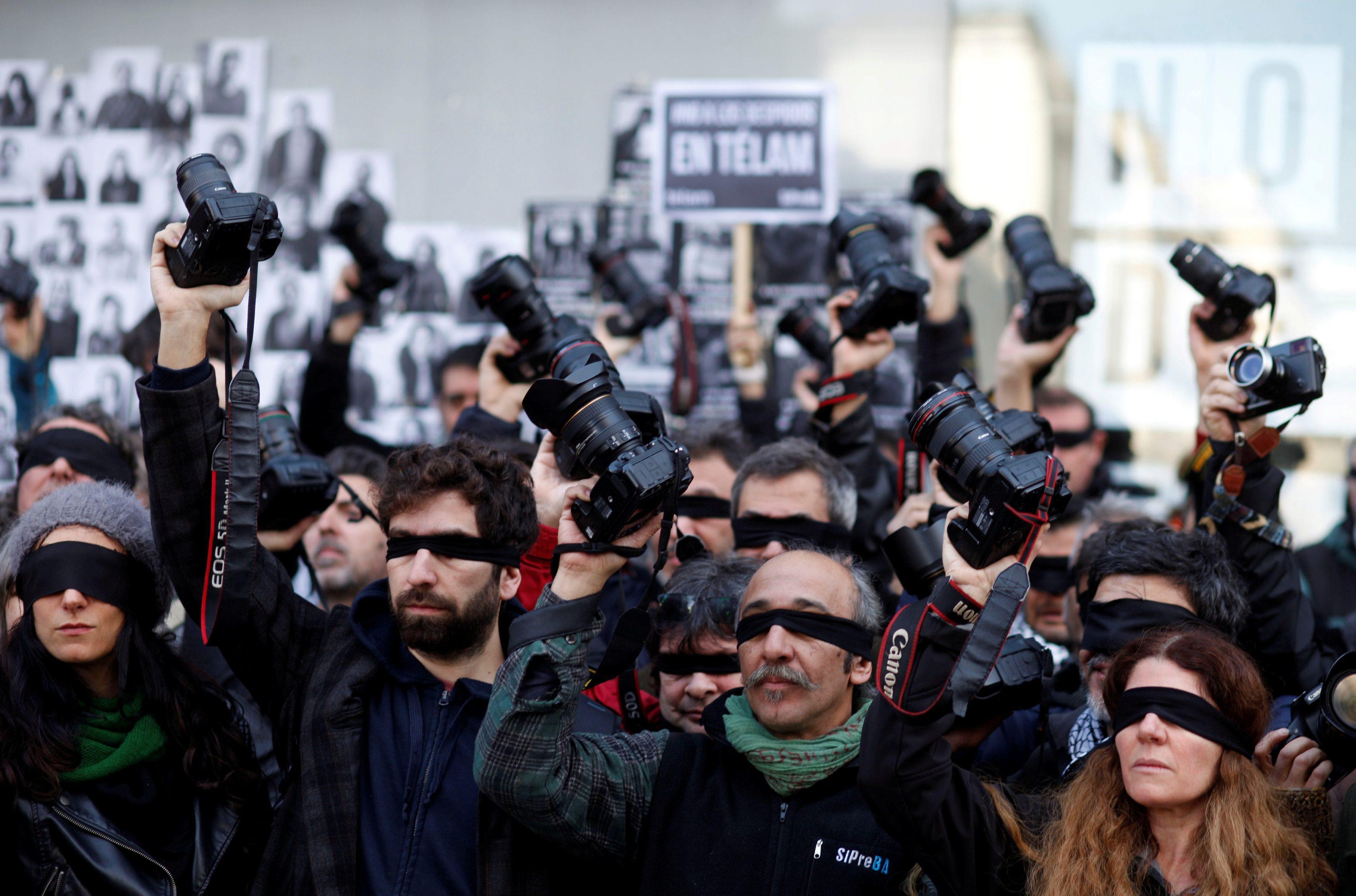 Blindfolded Argentine journalists hold up cameras during a protest against the layoff of over 300 em
