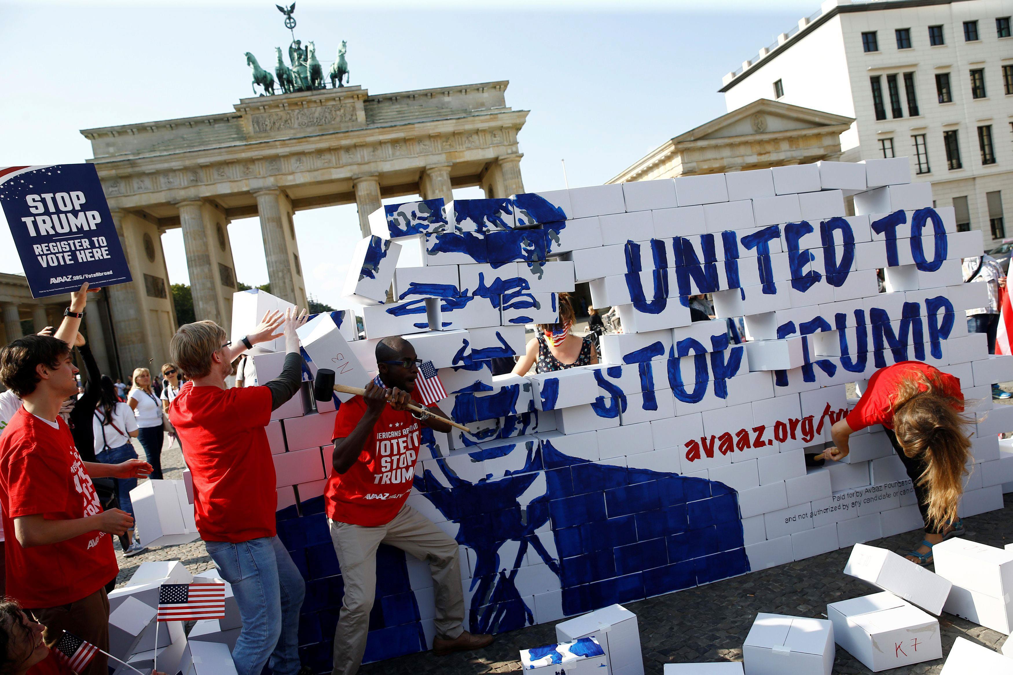 Campaigners pose on a 'United To Stop Trump' cardboard wall in front of the Brandenburg Gate to urge