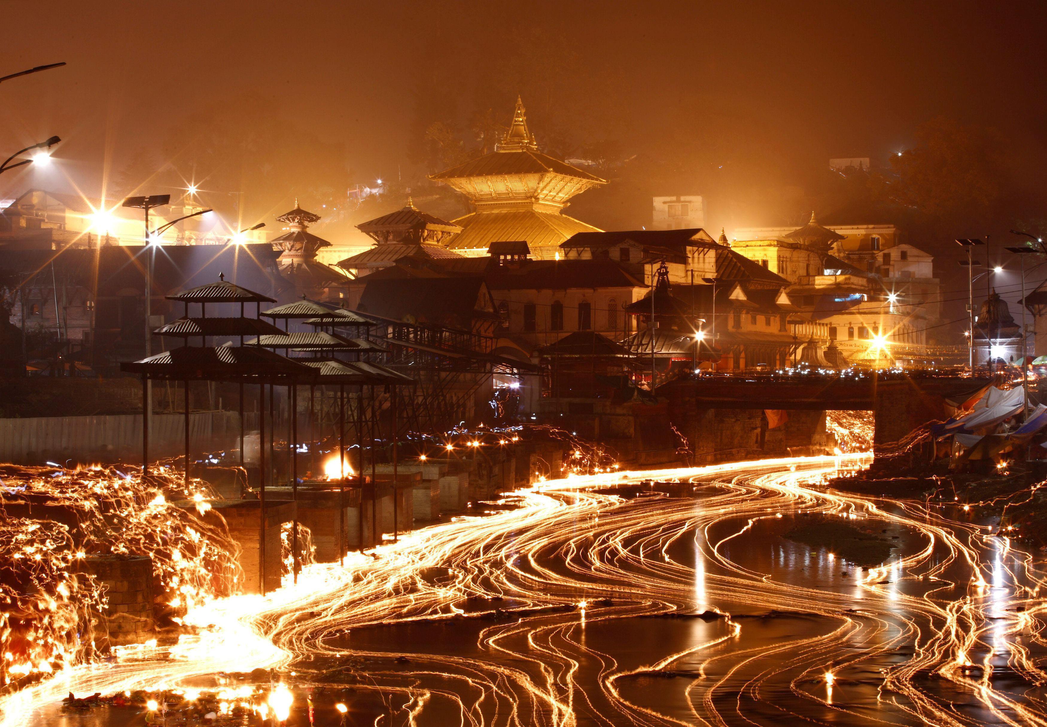 Oil lamps offered by devotees illuminate the Bagmati River flowing through the premises of the Pashu