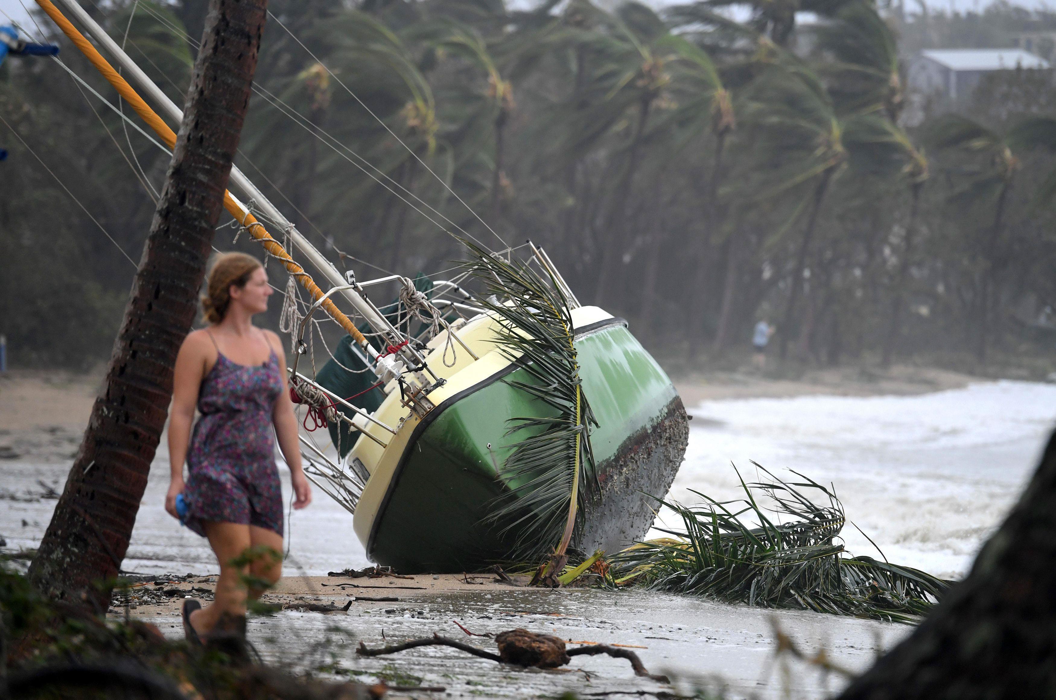 A local resident walks past a yacht that was washed ashore after Cyclone Debbie hit the northern Que