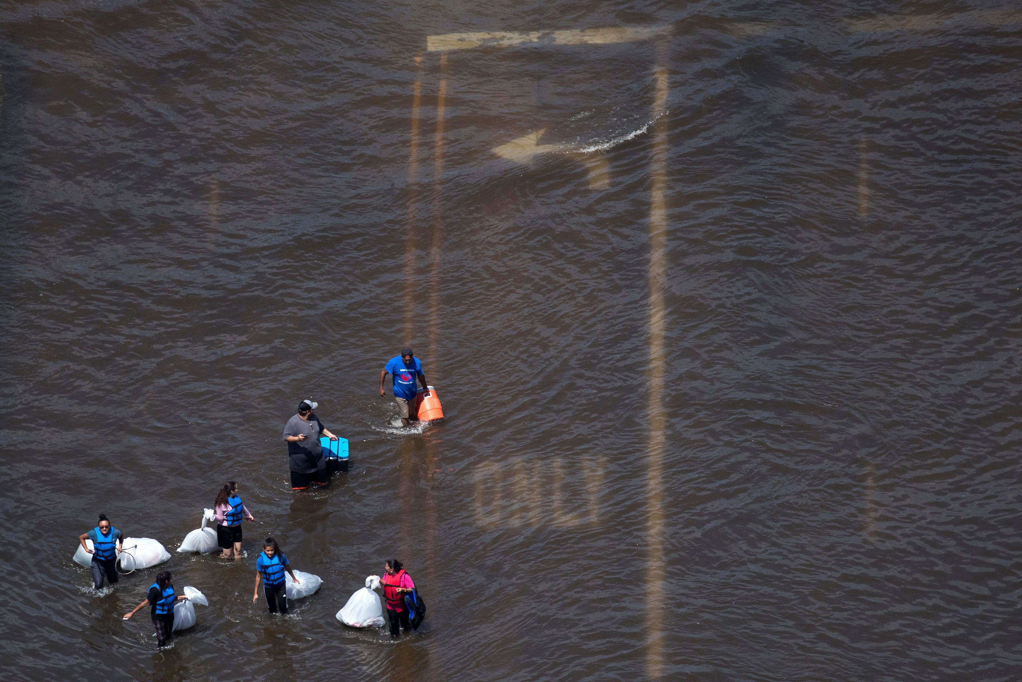 A group of people carry supplies through flood waters caused by Tropical Storm Harvey in Port Arthur