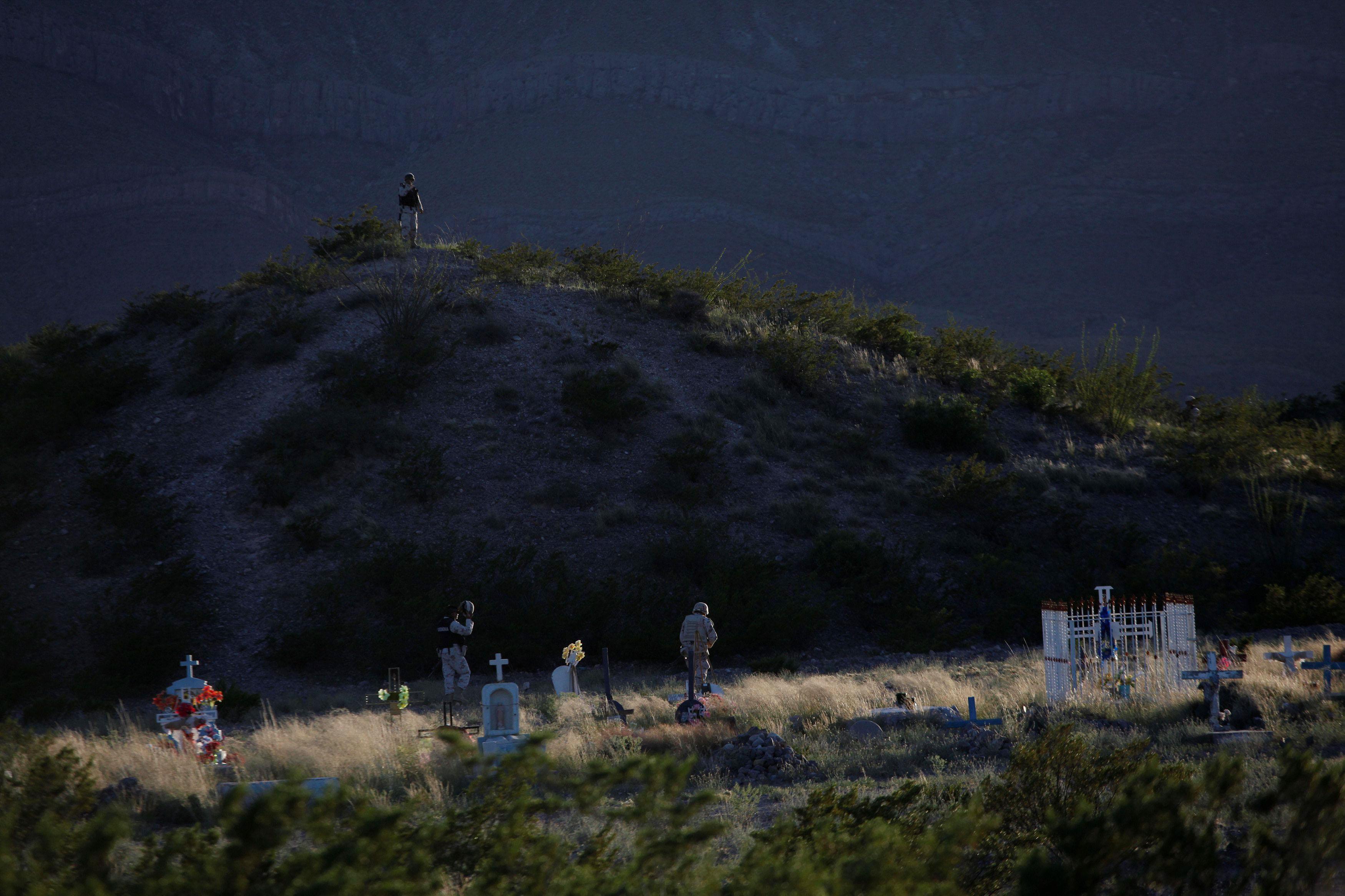 Soldiers patrol on foot at a cemetery after a gunfight with unknown assailants at Juarez Valley, on 