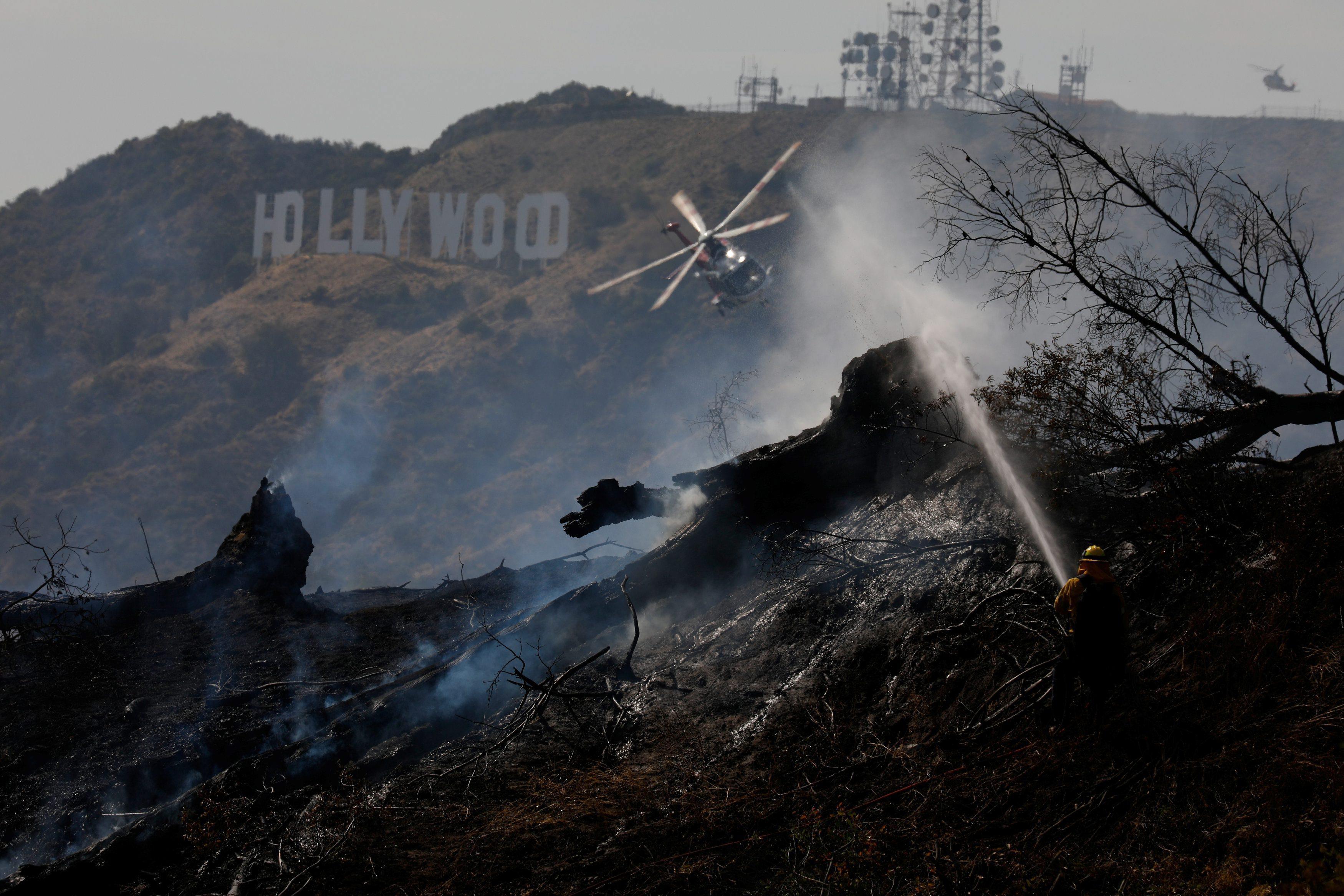 Firefighters work on a fire near the landmark Griffith Observatory in the hills overlooking the Holl