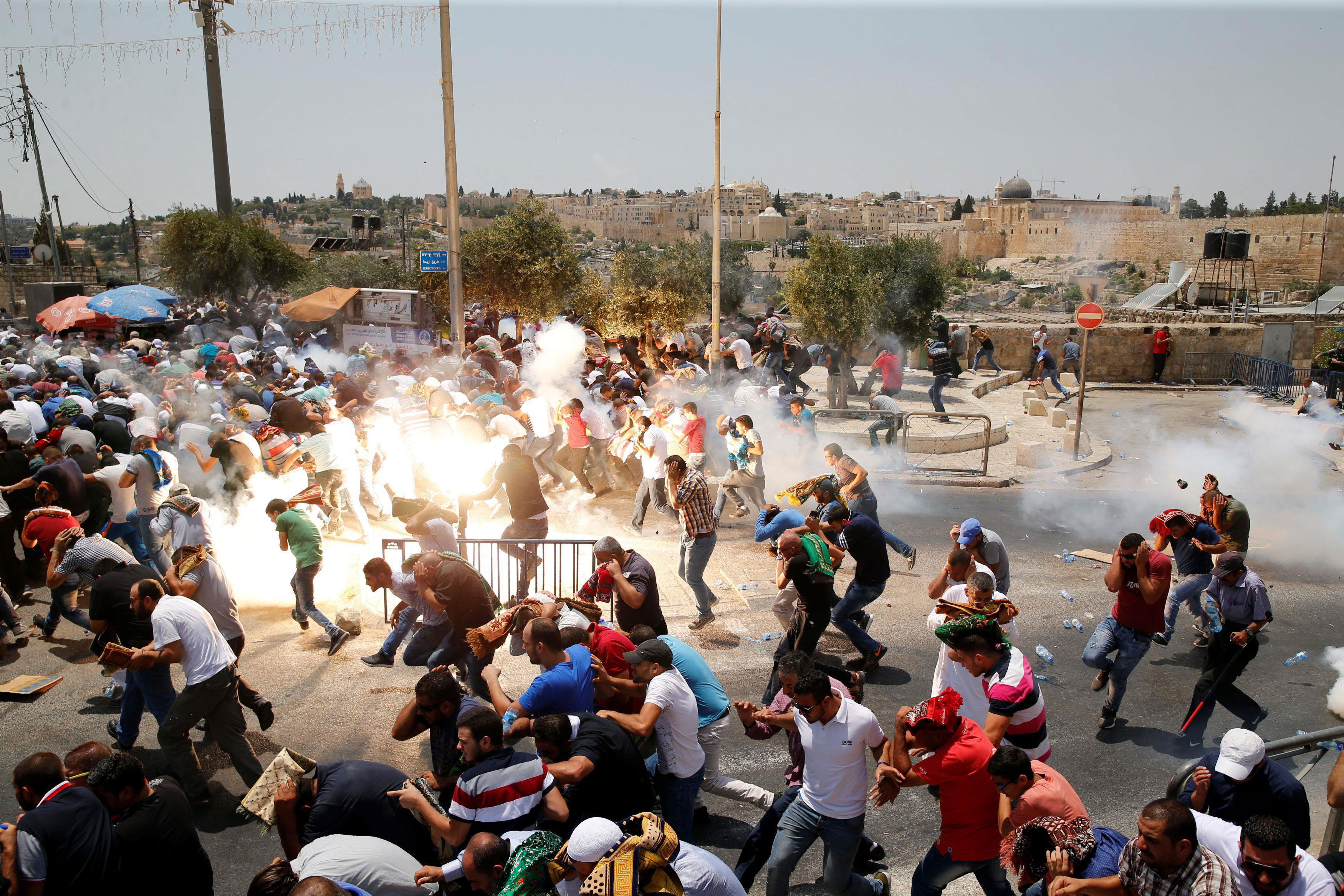 Palestinians react following tear gas that was shot by Israeli forces after Friday prayer on a stree