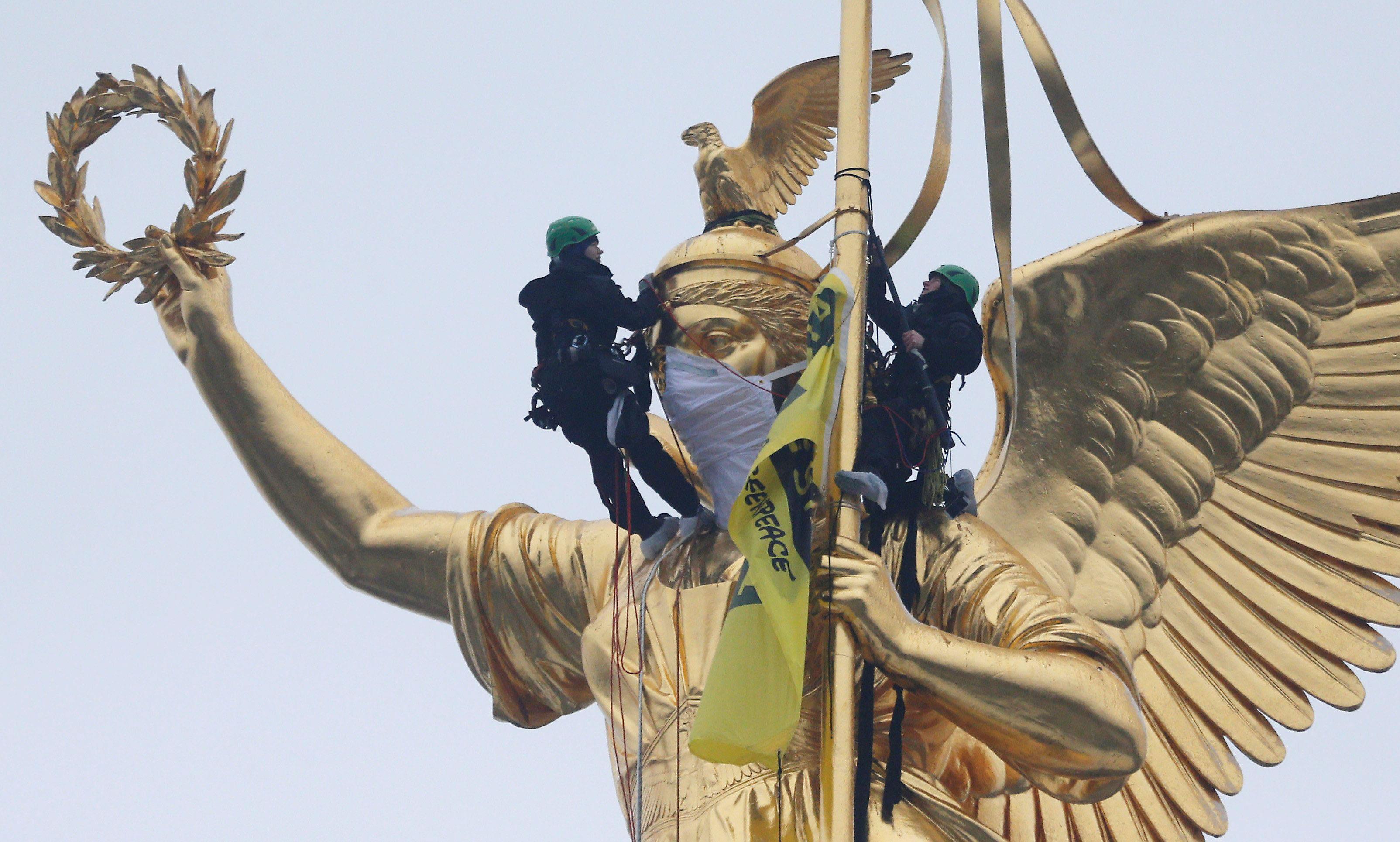 Greenpeace activists climb the Golden Victoria monument on top of the Victory Column and install a b