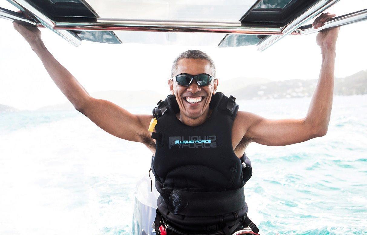 Former U.S. President Barack Obama sits on a boat during a kite surfing outing with British business