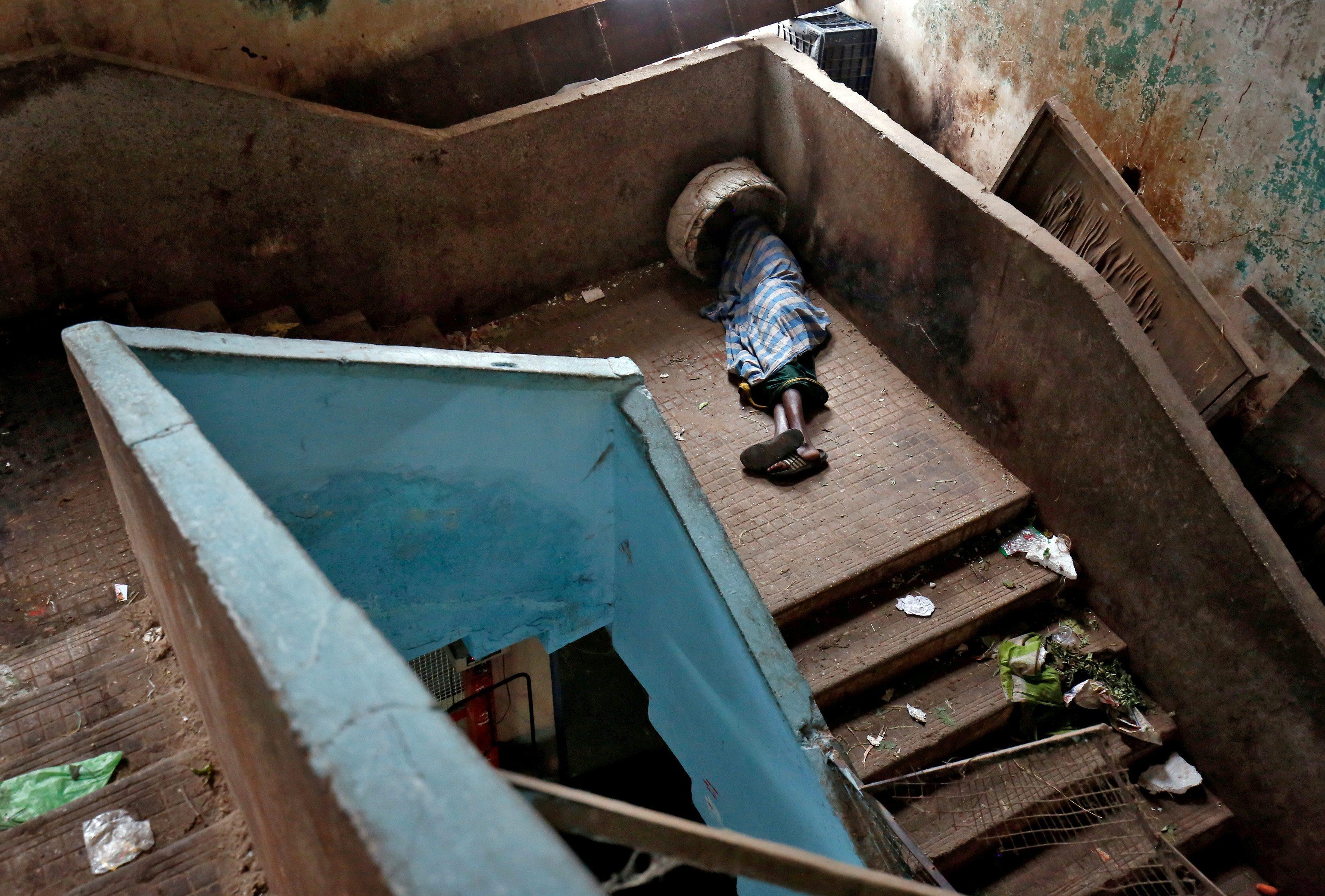 A porter sleeps on a stairway at a wholesale market in Bengaluru